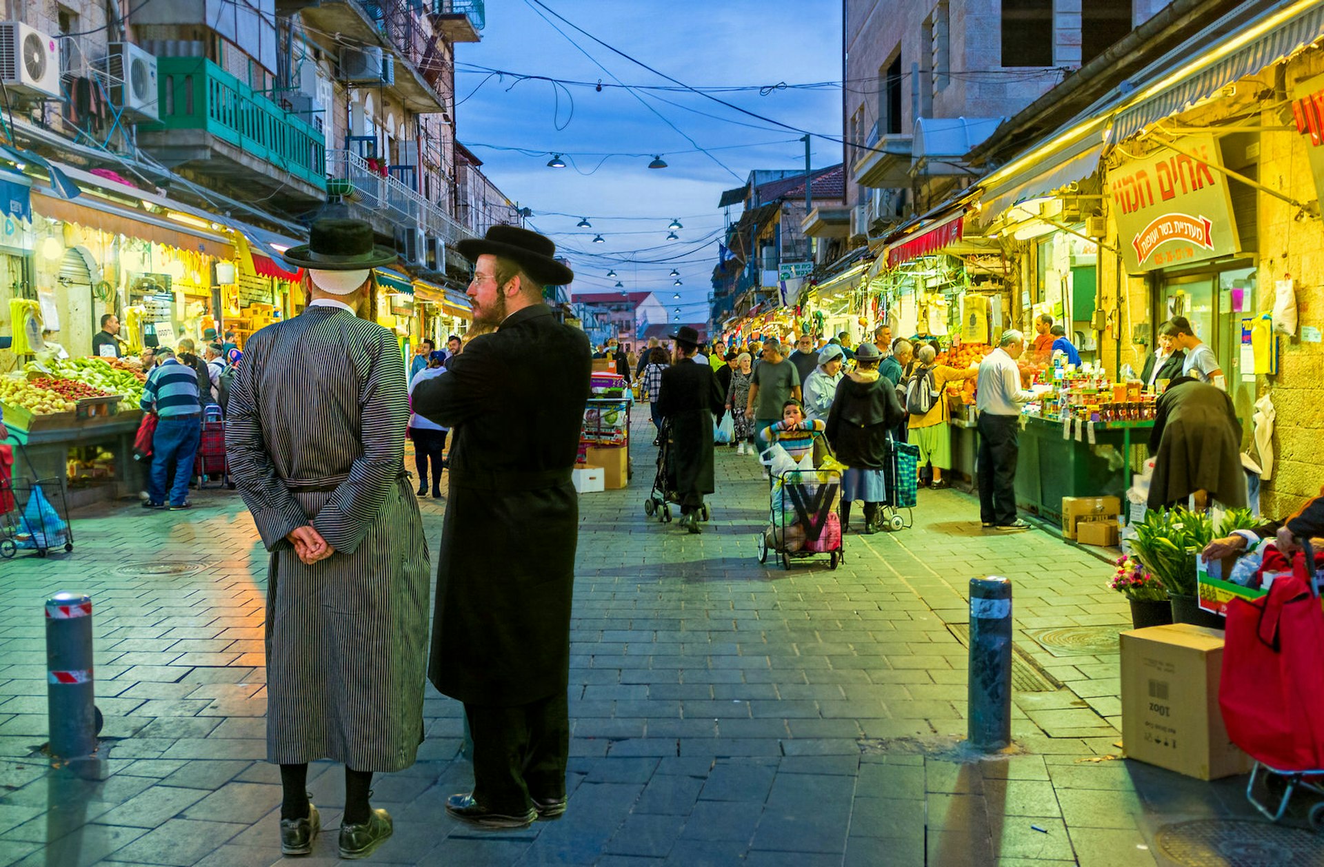 Two friends, dressed in traditional clothes, talking at the entrance of Mahane Yehuda market in Jerusalem.