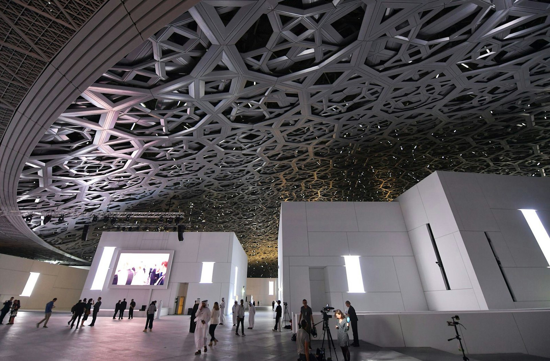 A general view shows people walking under the dome at the Louvre Abu Dhabi that was designed by French architect Jean Nouvel during its inauguration on November 8, 2017 on Saadiyat island in the Emirati capital. More than a decade in the making, the Louvre Abu Dhabi opened its doors, bringing the famed name to the Arab world for the first time. Image by Ludovic Marin / AFP / Getty Images