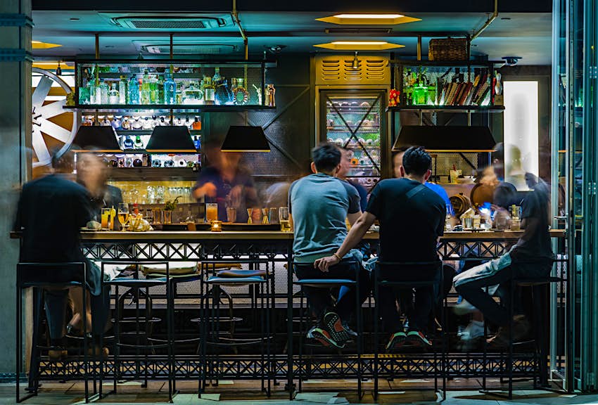 An assortment of people eat their food while sitting on high stools at a bar in Singapore © ZDL / Shutterstock