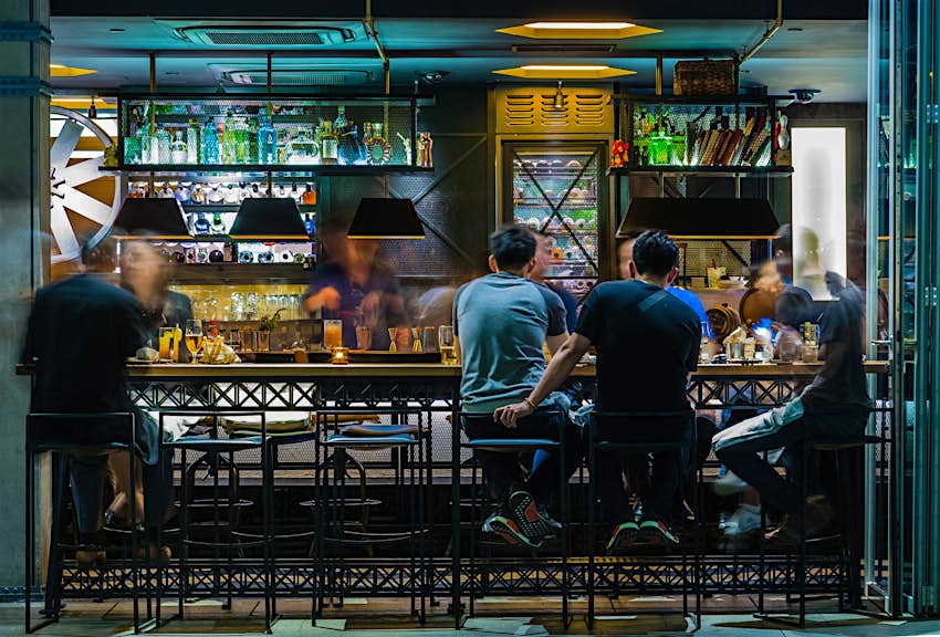 Features - shutterstockRF_645830119_1-b7c8b5ccd1c4 An assortment of people eat their food while sitting on high stools at a bar in Singapore © ZDL / Shutterstock