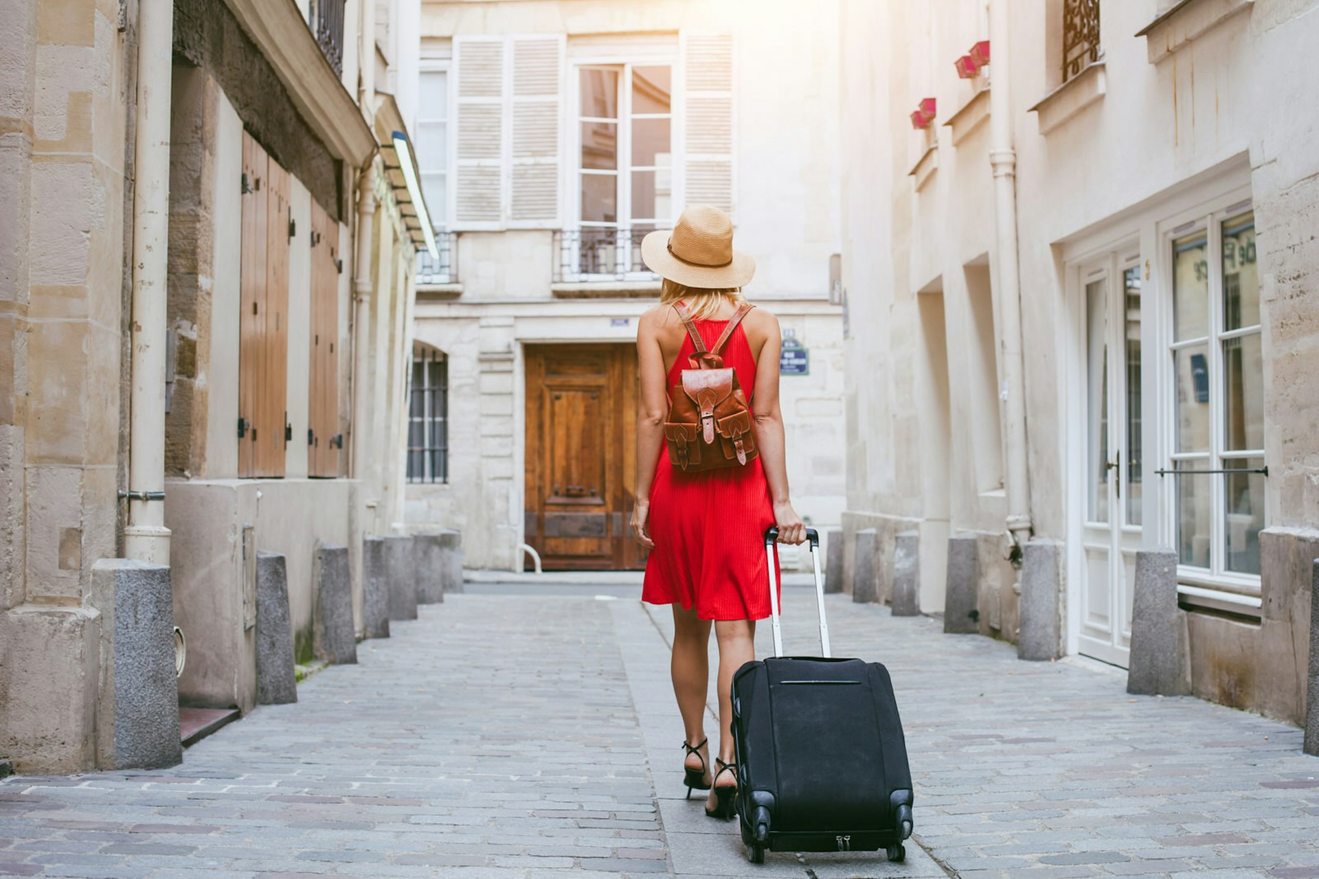 Travel predictions for 2018 - a woman walks down a street with a suitcase in Paris © Ditty_about_summer / Shutterstock