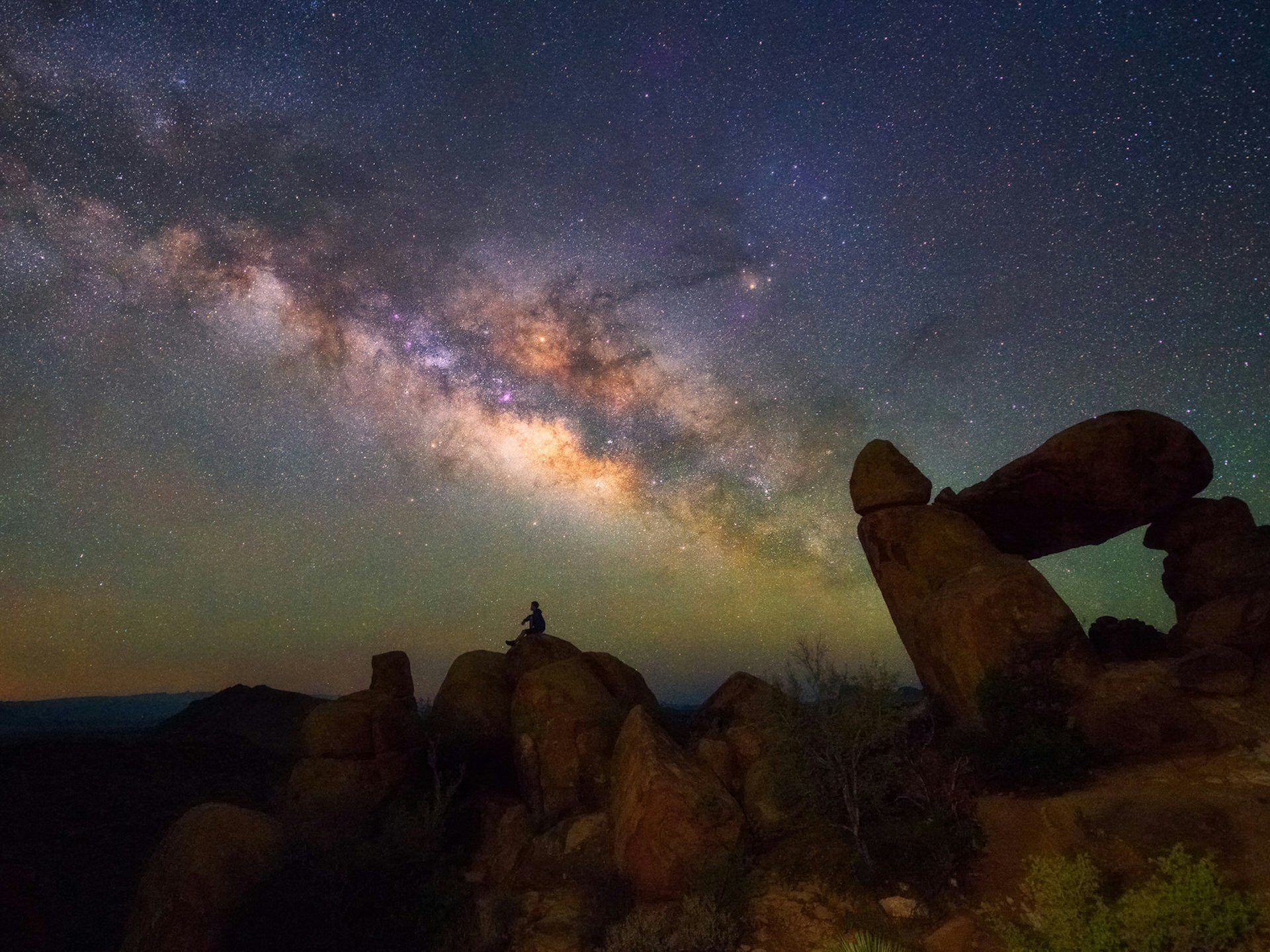 Man seated on a desert rock observing the Milky Way; Stargazing Southwest USA