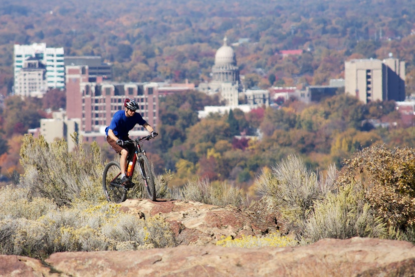 Mountain biker negotiating rocks through sage with downtown Boise in the background