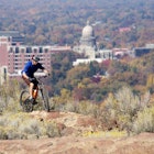 Mountain biker negotiating rocks through sage with downtown Boise in the background