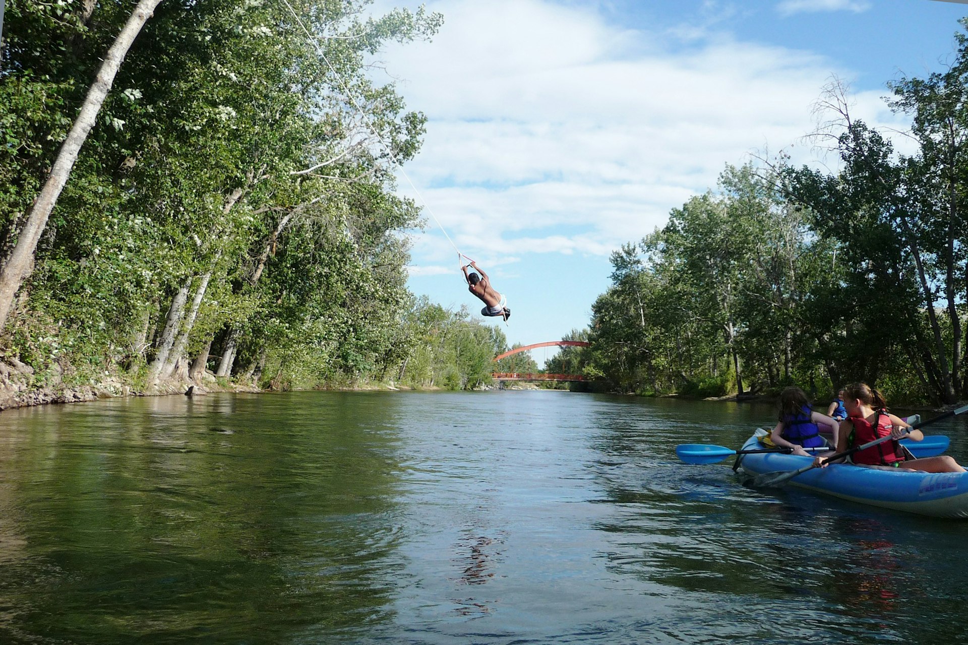 Rafters watch as someone flips off a rope swing into the Boise River