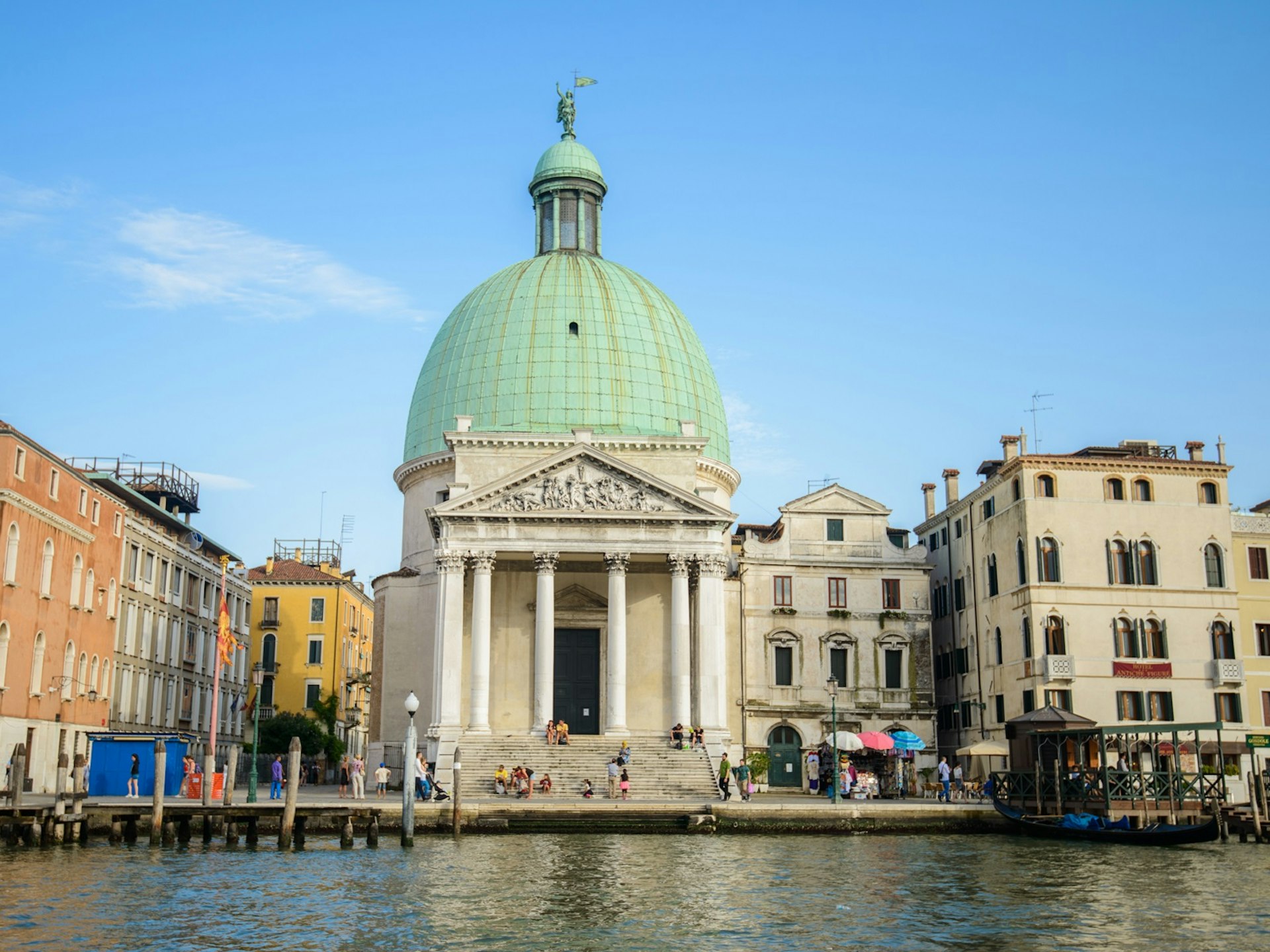 The dome of the Chiesa di San Simeone Piccolo is hard to overlook as it pierces into a clear blue sky sitting above the dark reflective waters of the canals in Santa Croce - Lonely Planet © red-feniks / Shutterstock