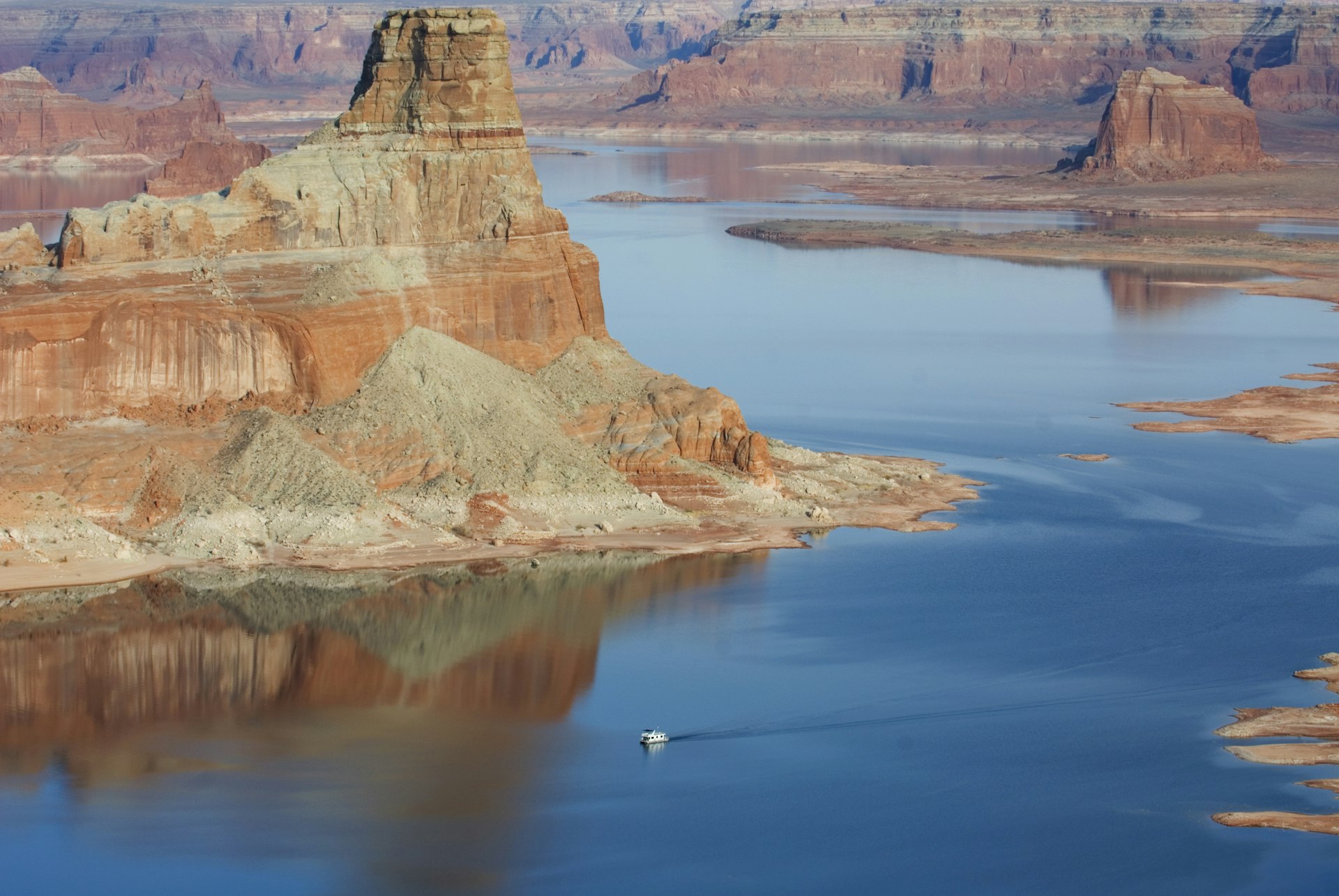 A houseboat navigates the towering canyons in Lake Powell