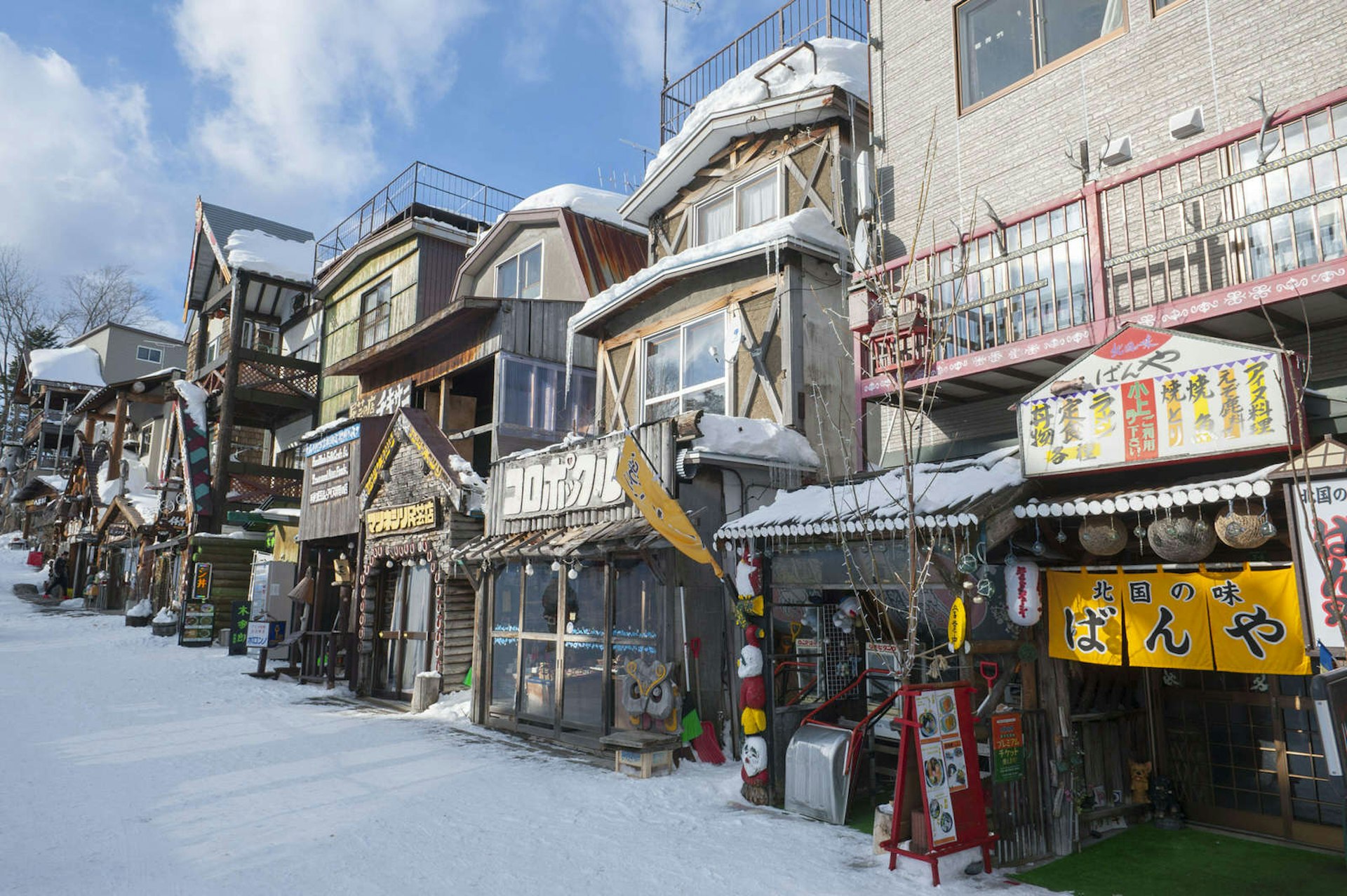 Rustic shops, restaurants and other business on a small snow-covered street in the Ainu Village