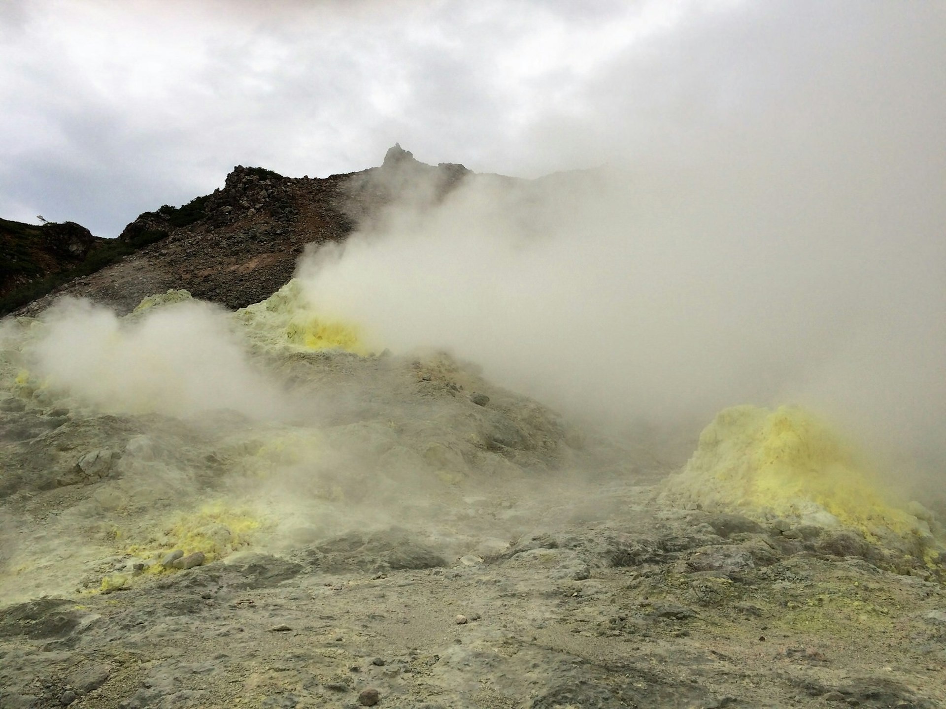 Steam rises out of sulphur-yellow-stained mounds on the slopes of mountain Io-zan