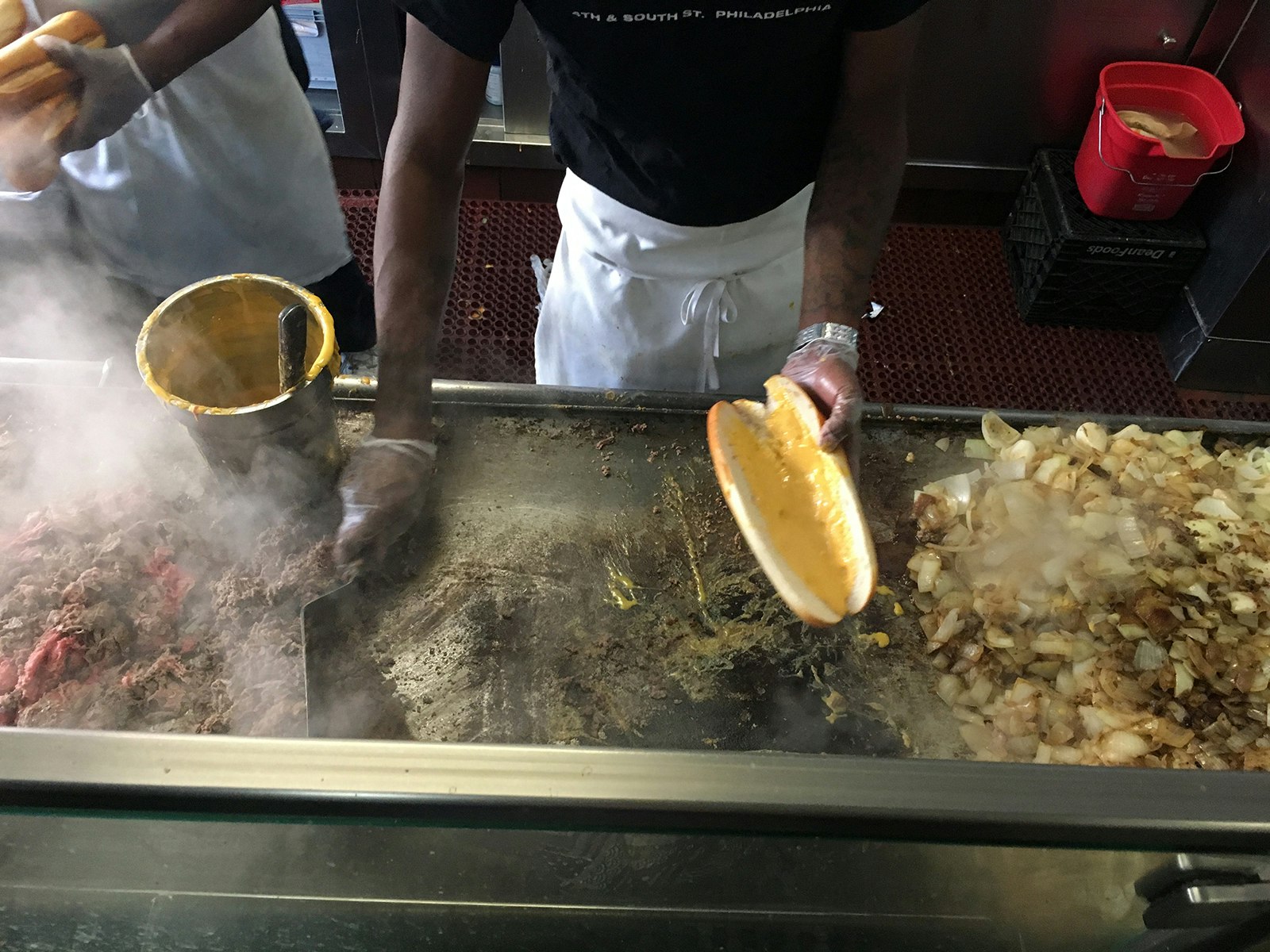 man cooks steak and onions over a hot grill at jim's steaks in philadelphia