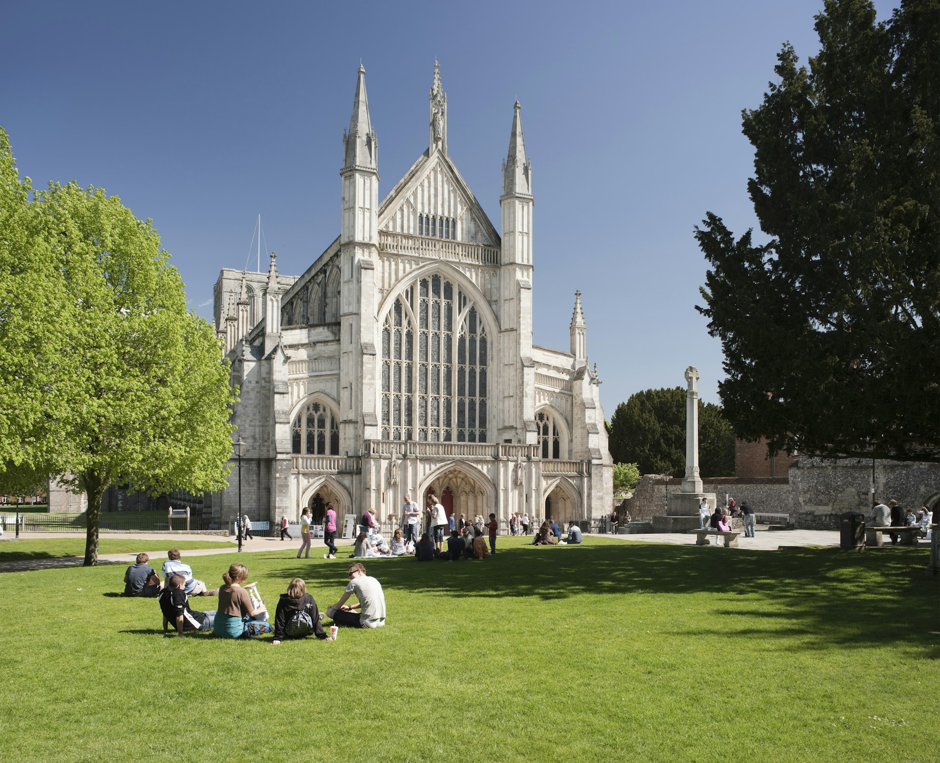 Pessoas sentam-se na grama em um dia ensolarado em frente à Catedral de Winchester, em Winchester, Inglaterra