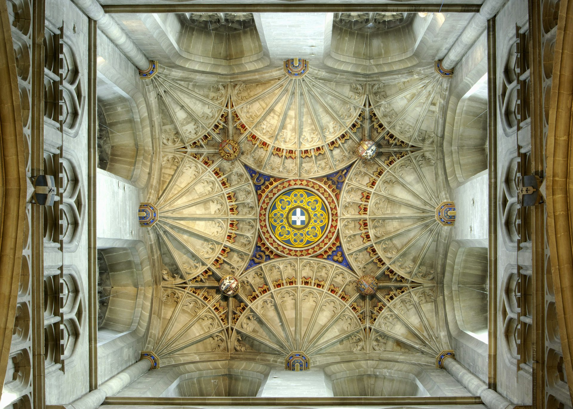The arches of Canterbury Cathedral's magnificent ceiling with a gold and blue crest in the center