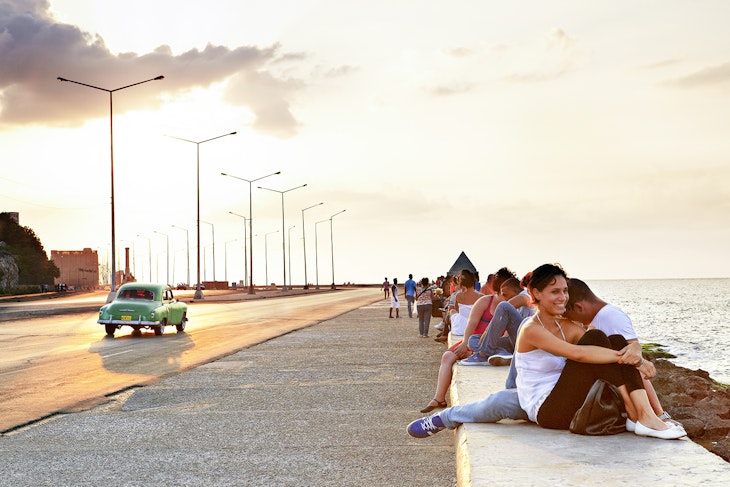 Features - People gathered beside waterfront on Malecon at sunset.