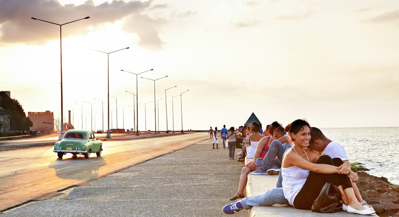 Features - People gathered beside waterfront on Malecon at sunset.