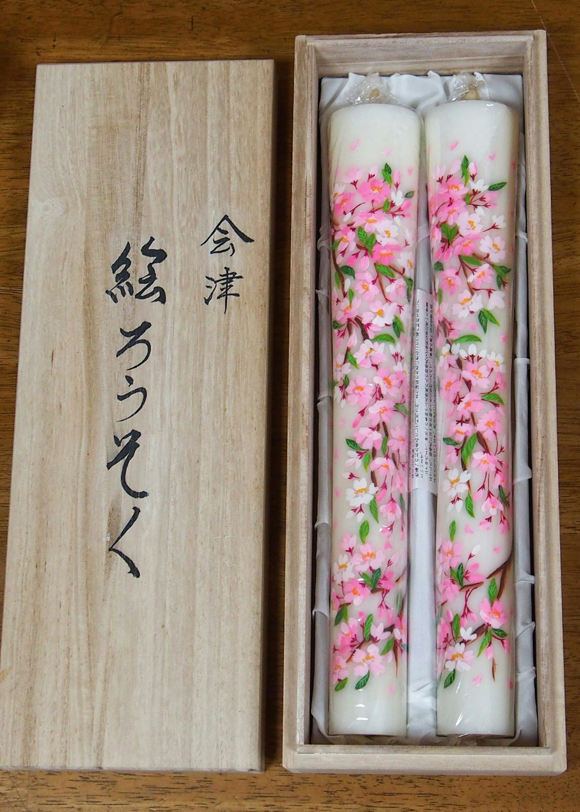 Two Aizu Erōsoku candles, finely painted with pink blossoms, presented in a wooden box at studio Yamada Shōten © Manami Okazaki / Lonely Planet