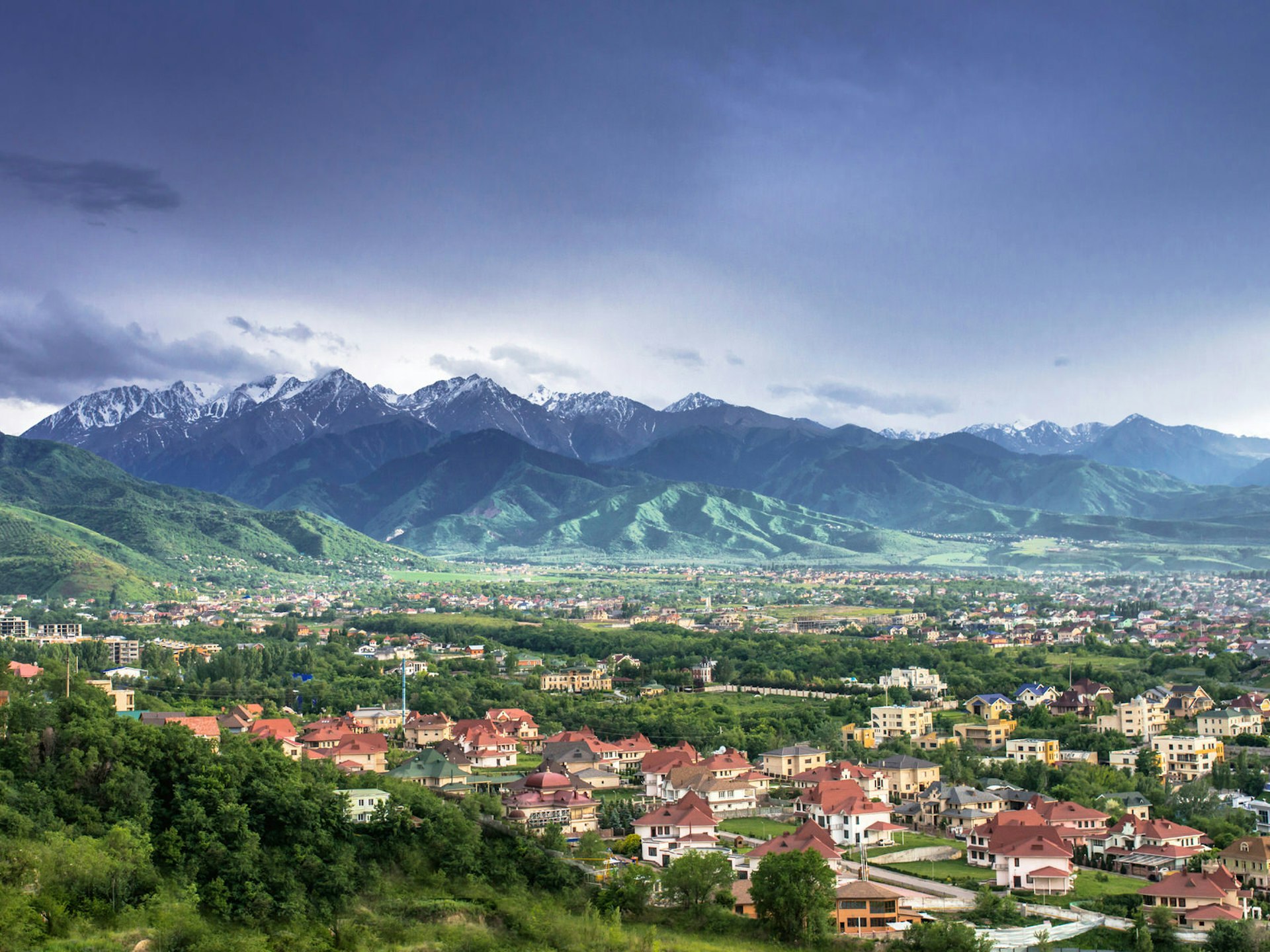 View of Almaty with red-roofed houses and snow-capped mountains in the distance The mountains and deserts of Kazakhstan's southern wilderness is right on Almaty's doorstep © Aureliy / Shutterstock