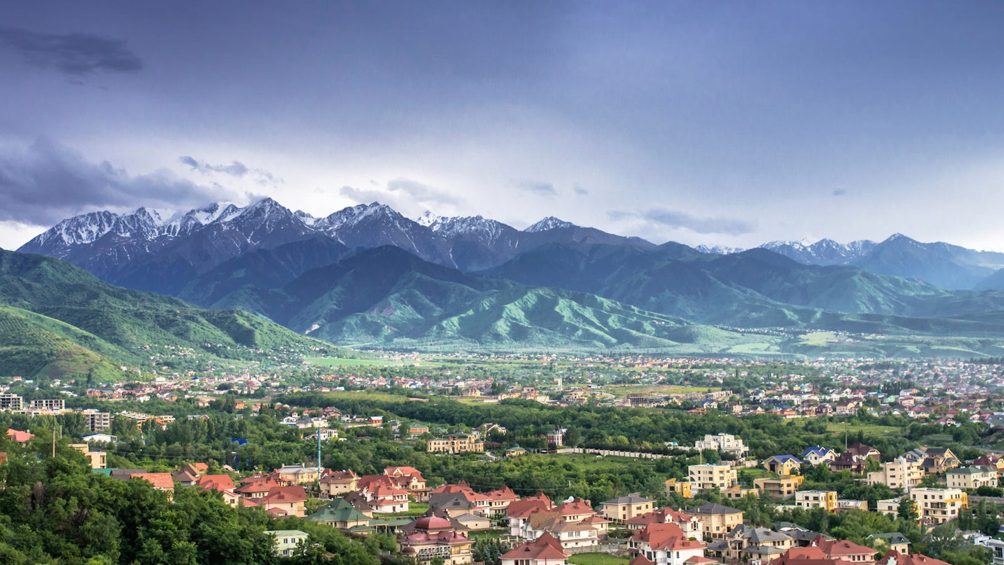 View of Almaty with red-roofed houses and snow-capped mountains in the distance The mountains and deserts of Kazakhstan's southern wilderness is right on Almaty's doorstep © Aureliy / Shutterstock
