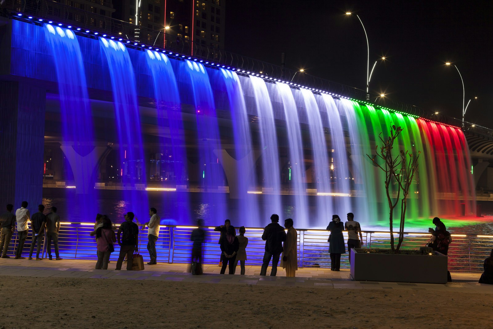 Colorful illuminated waterfall in Dubai. The waterfall is part of the Dubai Water Canal development. United Arab Emirates, Middle East.