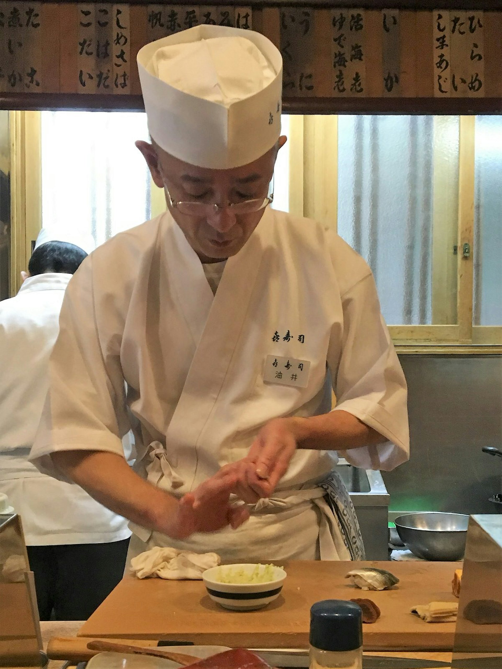 A sushi chef works behind the counter at Kizushi, using his hands to create sushi pieces