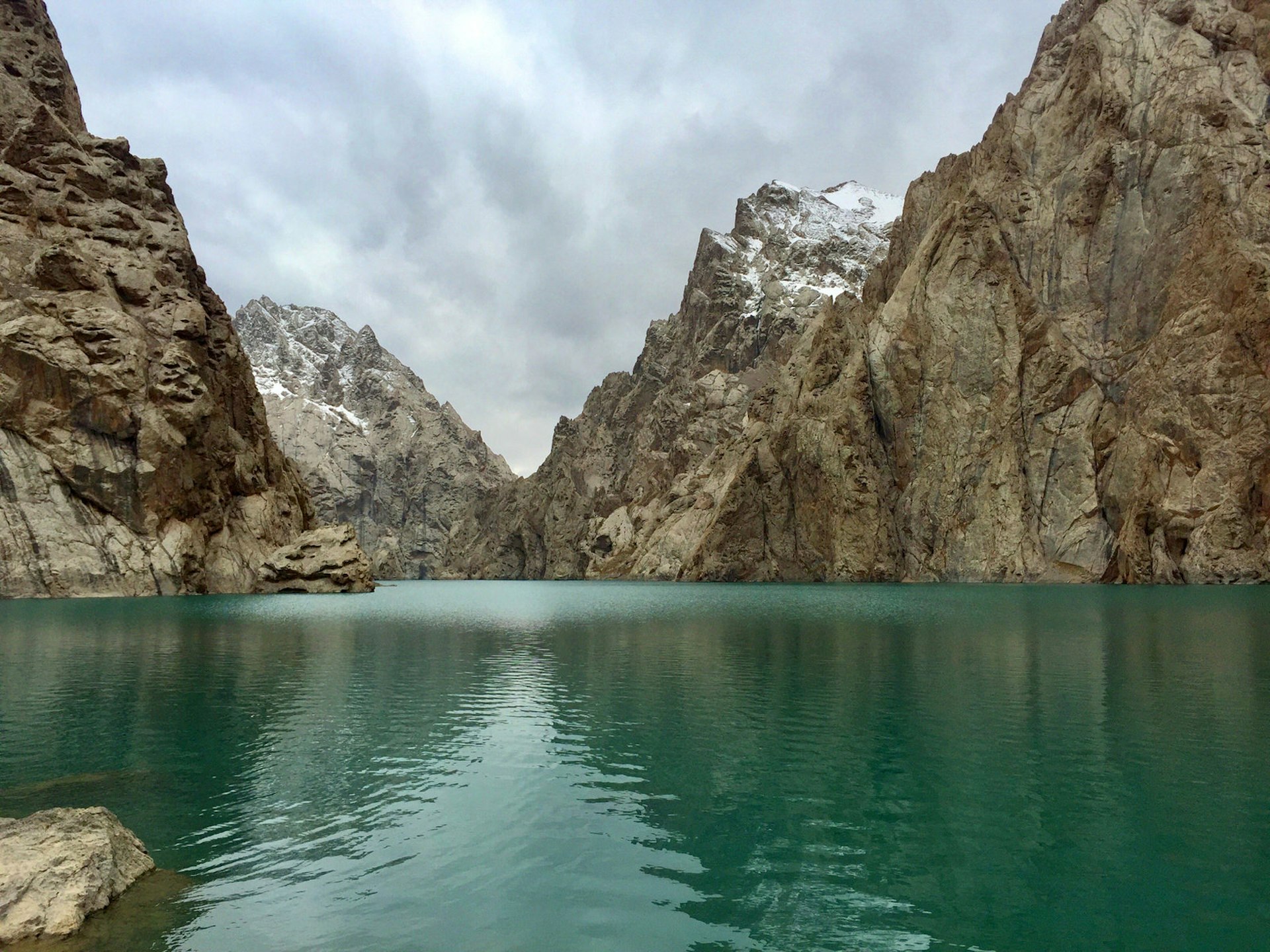 A turquoise lake framed by sharp grey mountain peaks and white snow clouds © Megan Eaves / Lonely Planet