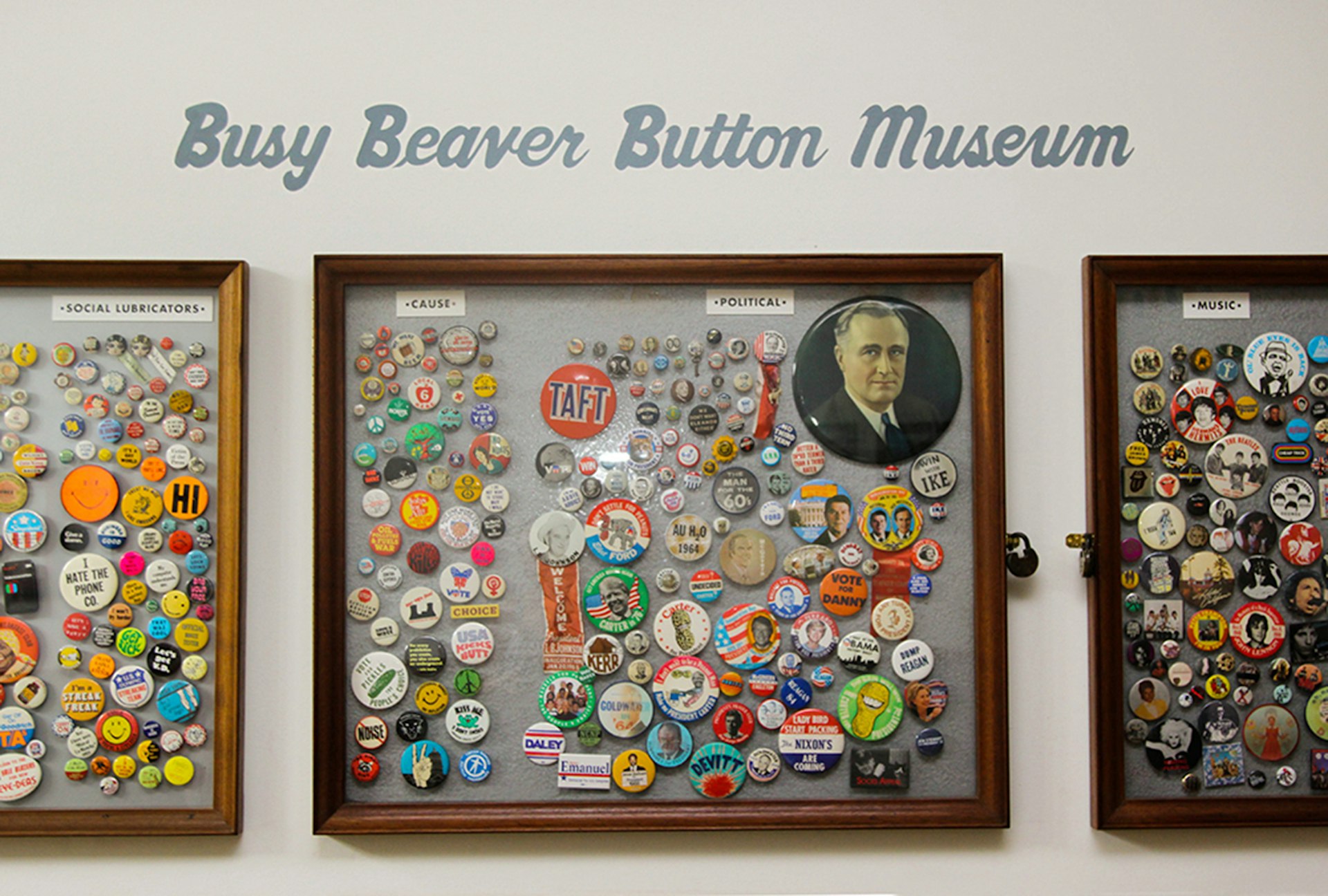 dozens of pin-back buttons are clustered in glass display cases hung on a wall