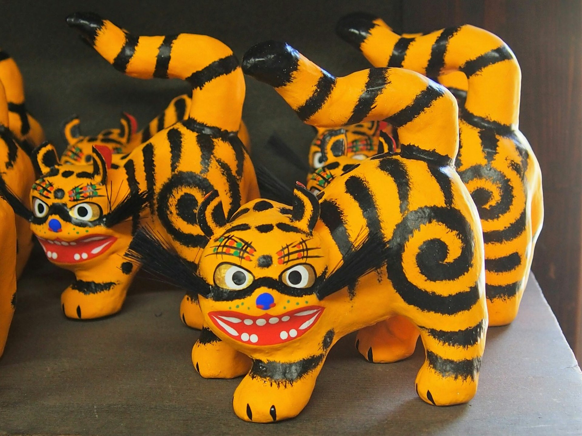 Close up of three papier-mache tigers, brightly painted in orange and black © Manami Okazaki / Lonely Planet