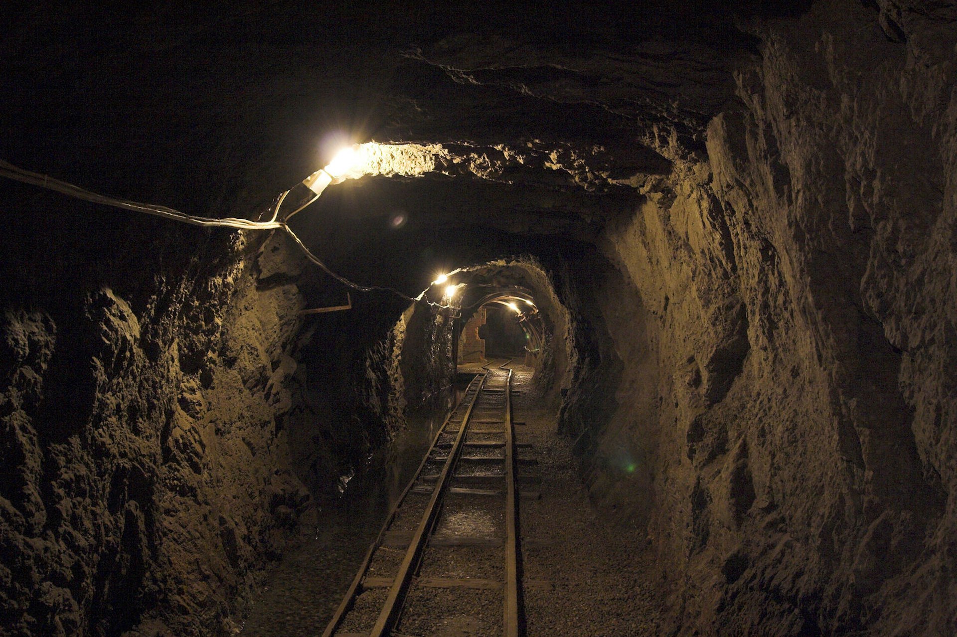 An internal view of a dark mine tunnel in Poland with train tracks running off into the distance