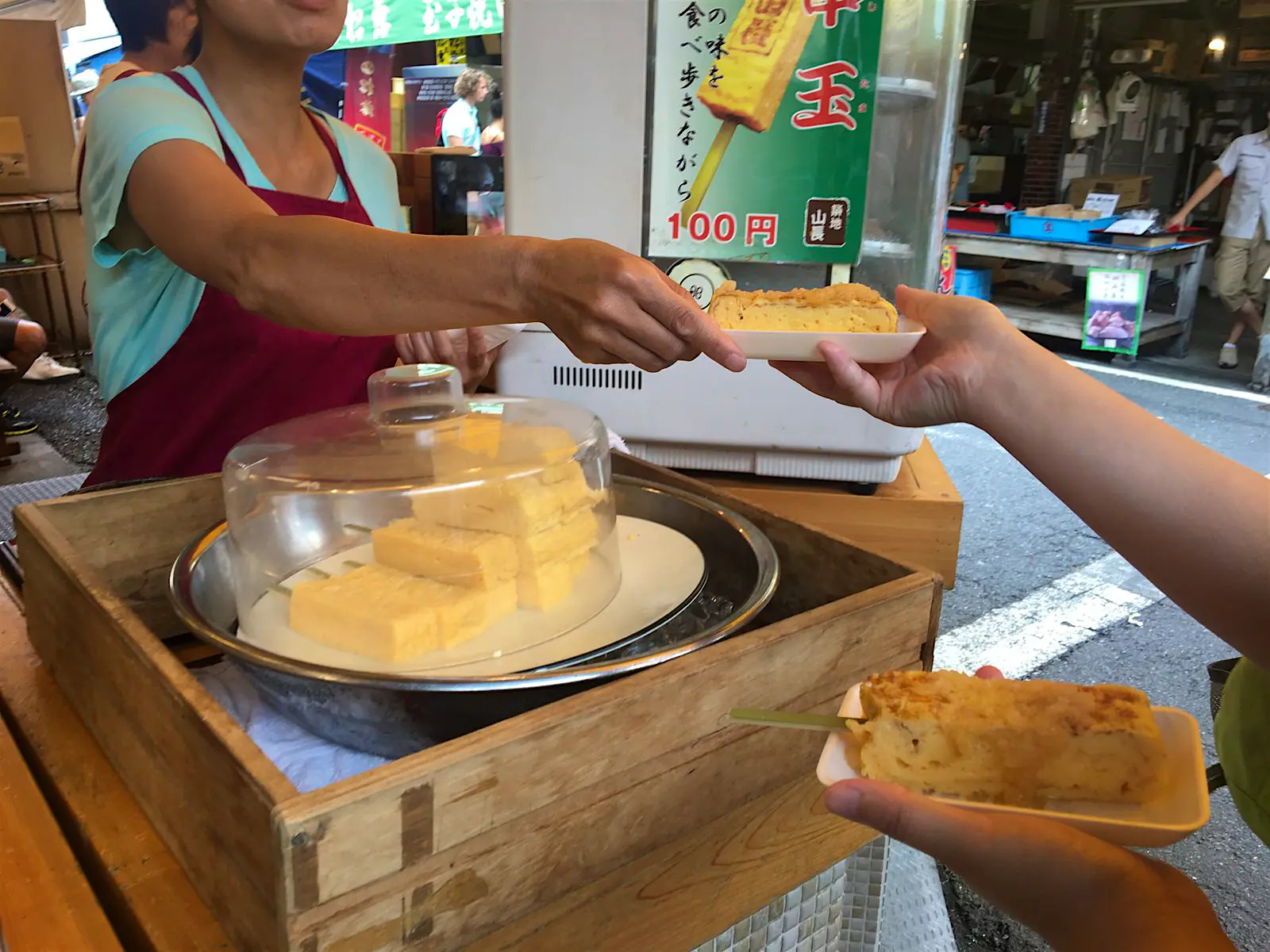 Features - yamacho_tokyo-2545ebc0b616 Staff member at Yamachō hands a plat of rolled omelette (tamago-yaki) to a customer © Rebecca Milner / Lonely Planet