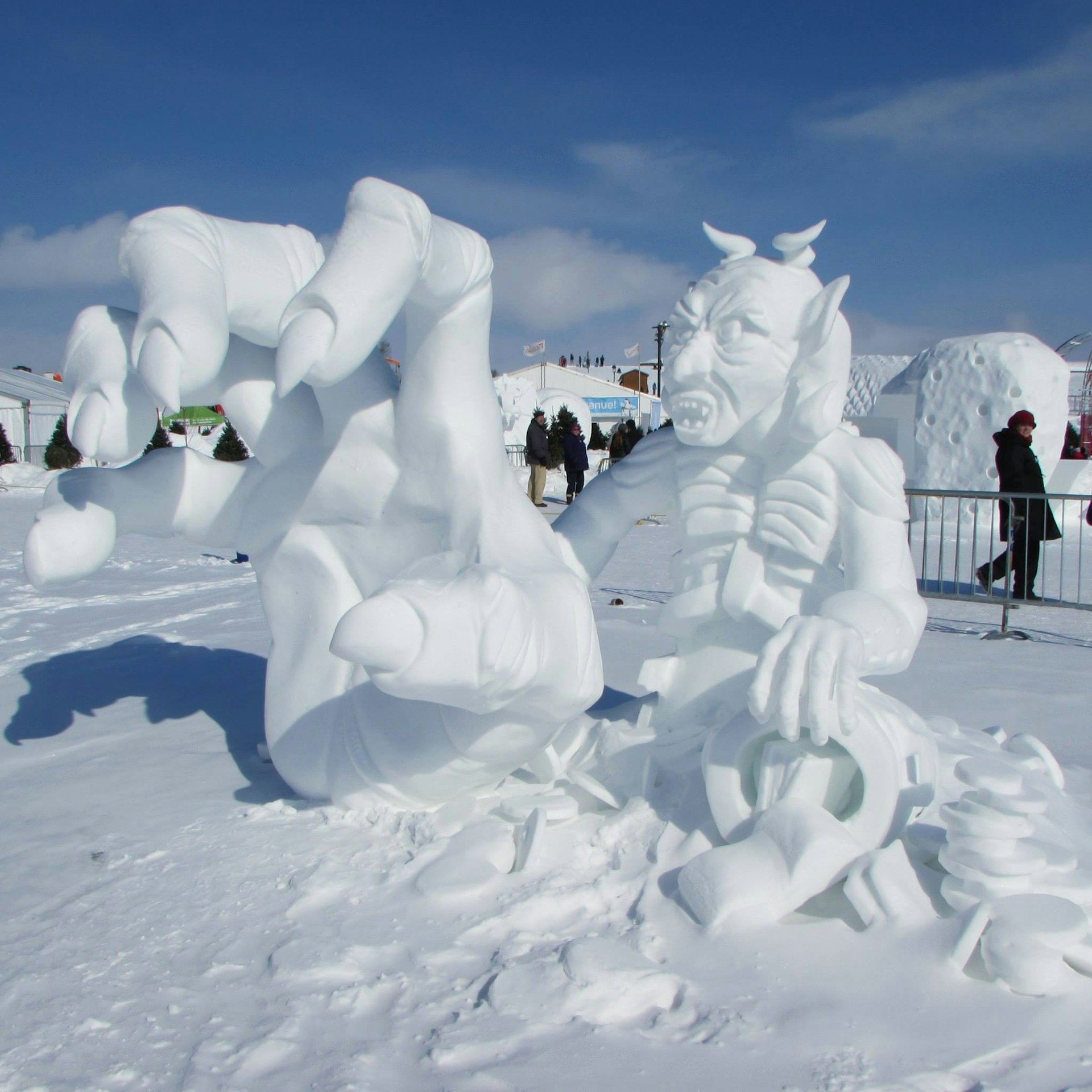 A larger-than-life size sculpture of a demon, with his hand outstretched to the camera, is carved from snow and ice in Québec City.