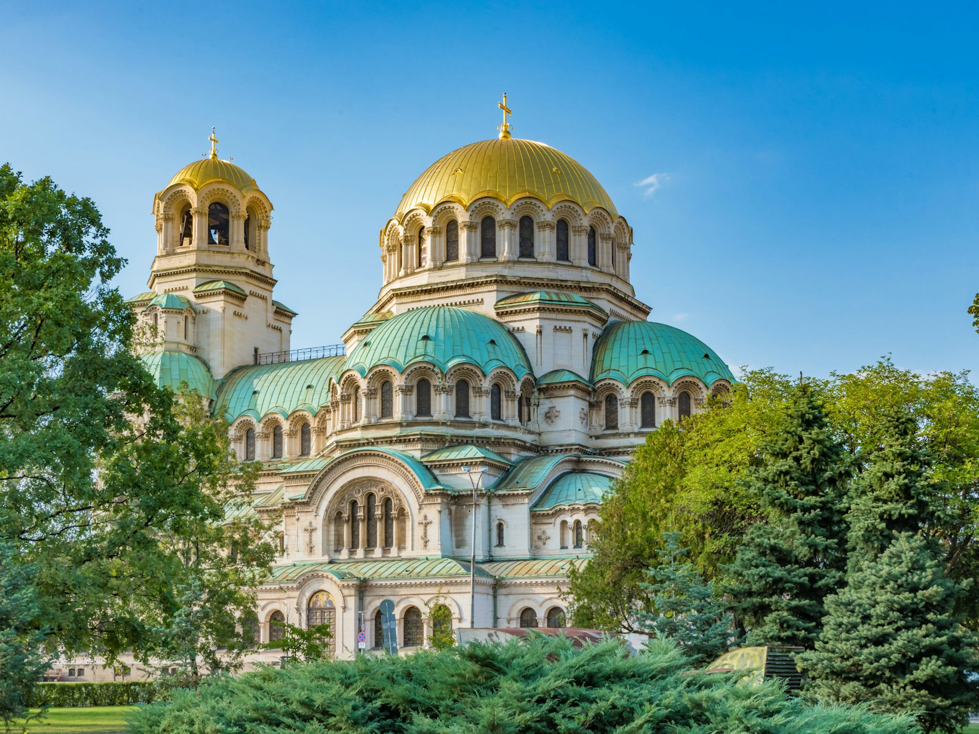 A large white church with several domed roofs in gold and teal colours