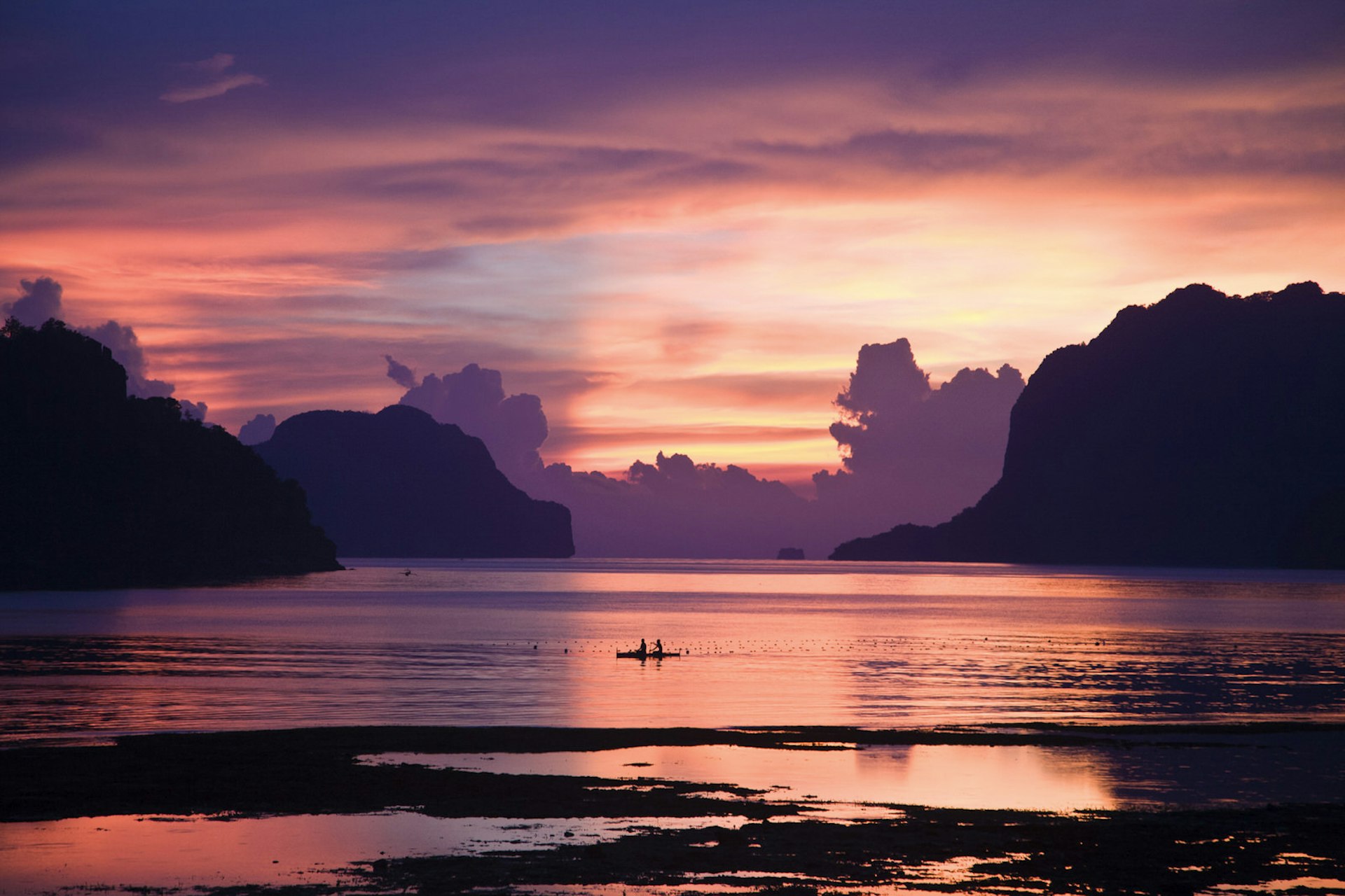 Two people on a kayak crossing Bacuit Bay, Palawan, at sunset © Mark Watson/Highlux / Getty Images