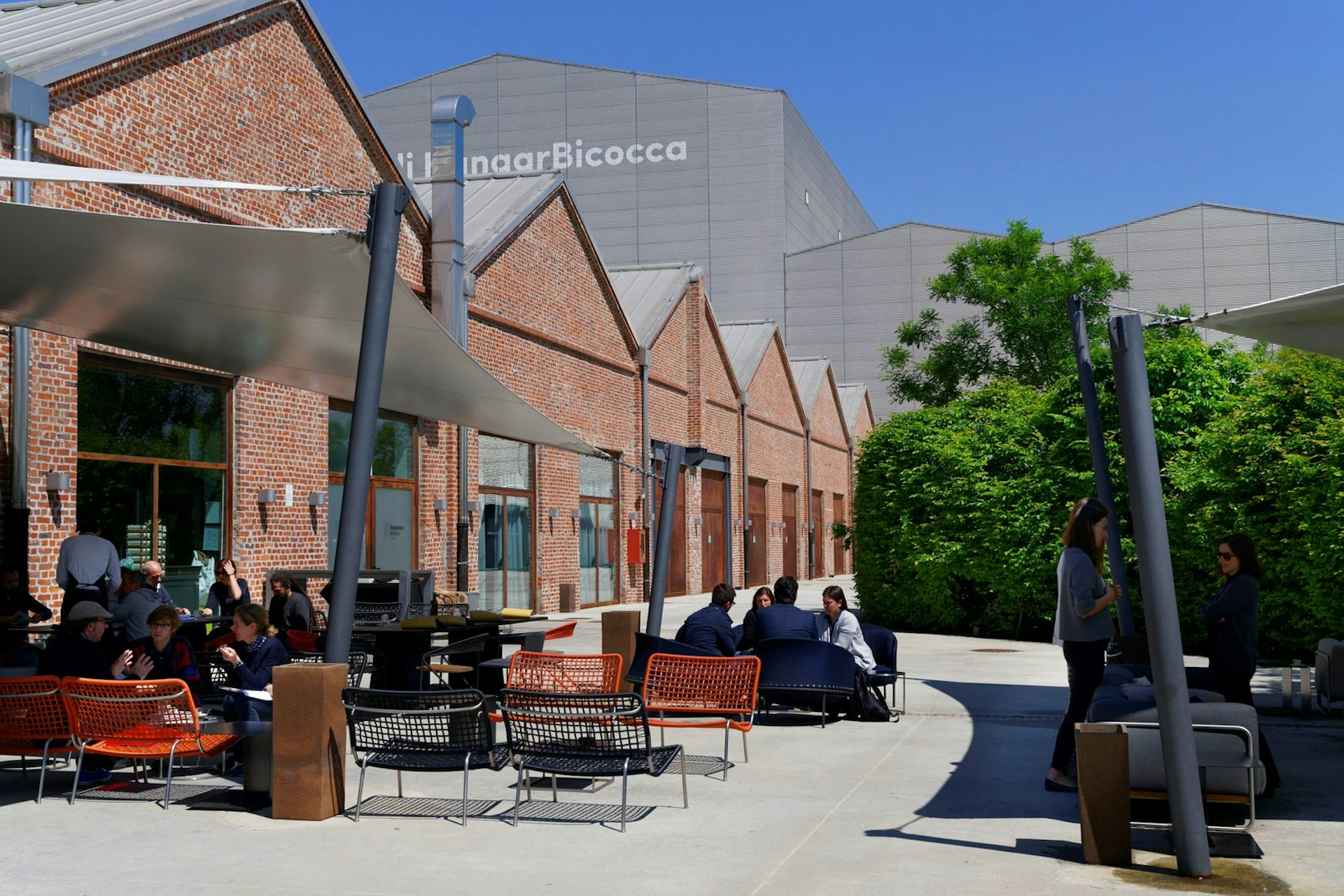 People sit on outside table in a cafe at the Hangar Bicocca