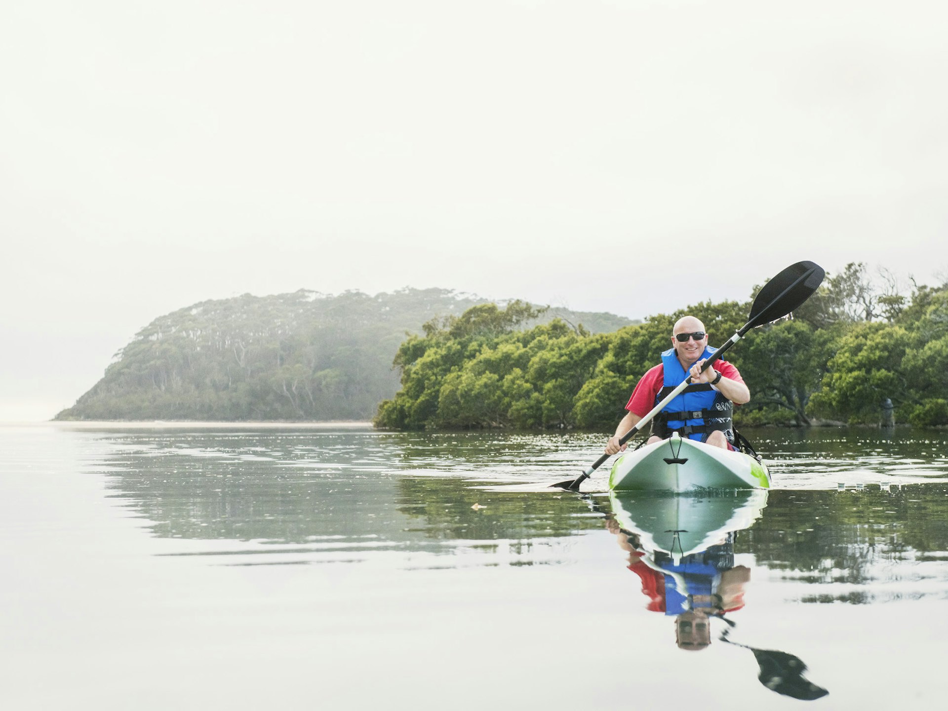 A man kayaking down the calm waters of the Narrawallee inlet