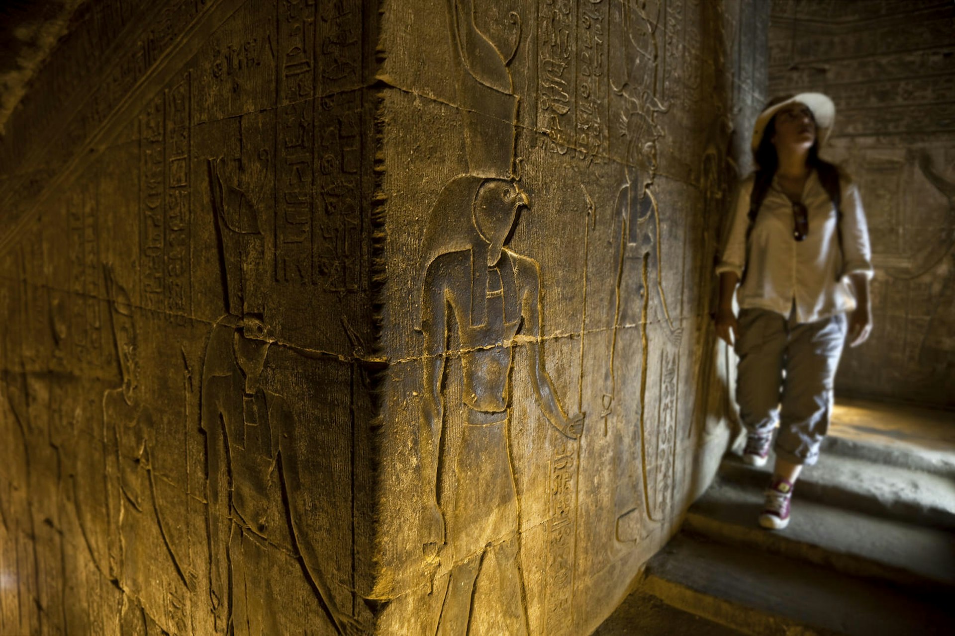 Woman in temple looking at hieroglyphics and Horus at Edfu temple. Image by ugurhan / Getty Images