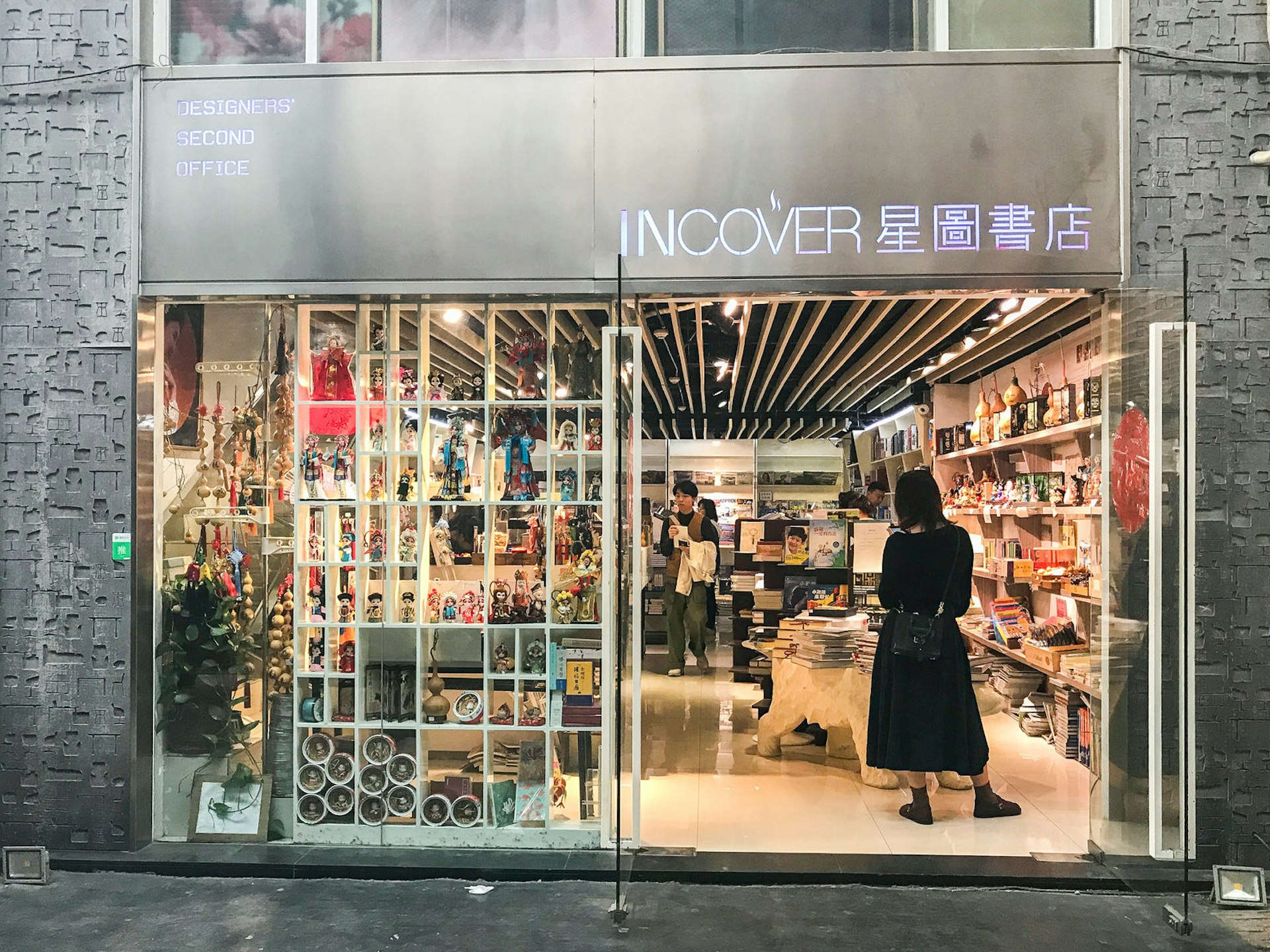 A woman in a black outfit stands in the door of a shop with a metal sign and small gifts decorating the walls. Incover, inside the OCT Loft complex, sells quirky designer gifts © Cathy Adams / Lonely Planet