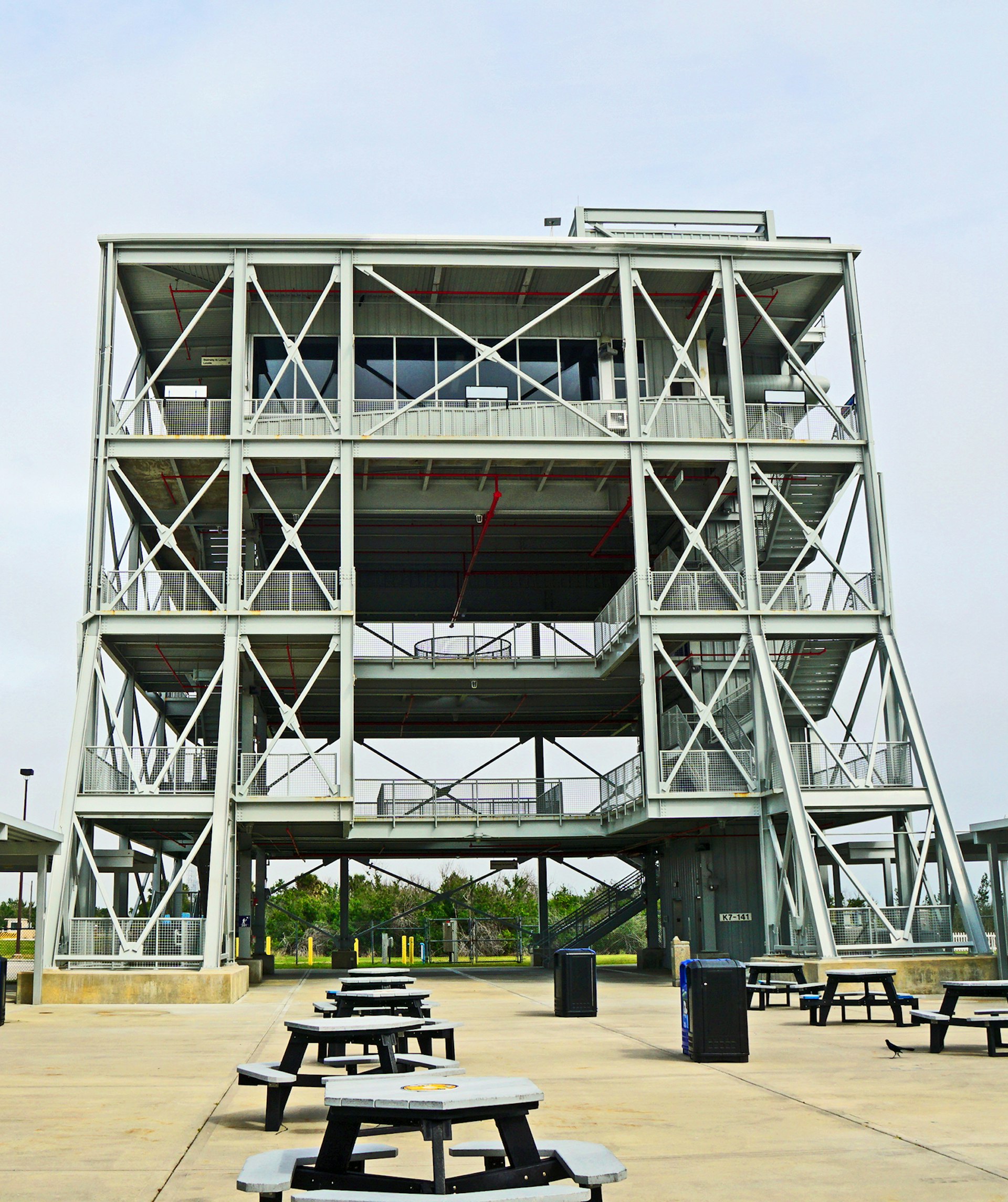 rear view of the LC-39 observation gantry on a gray day, with a few picnic tables scattered around; how to experience a rocket launch in Florida