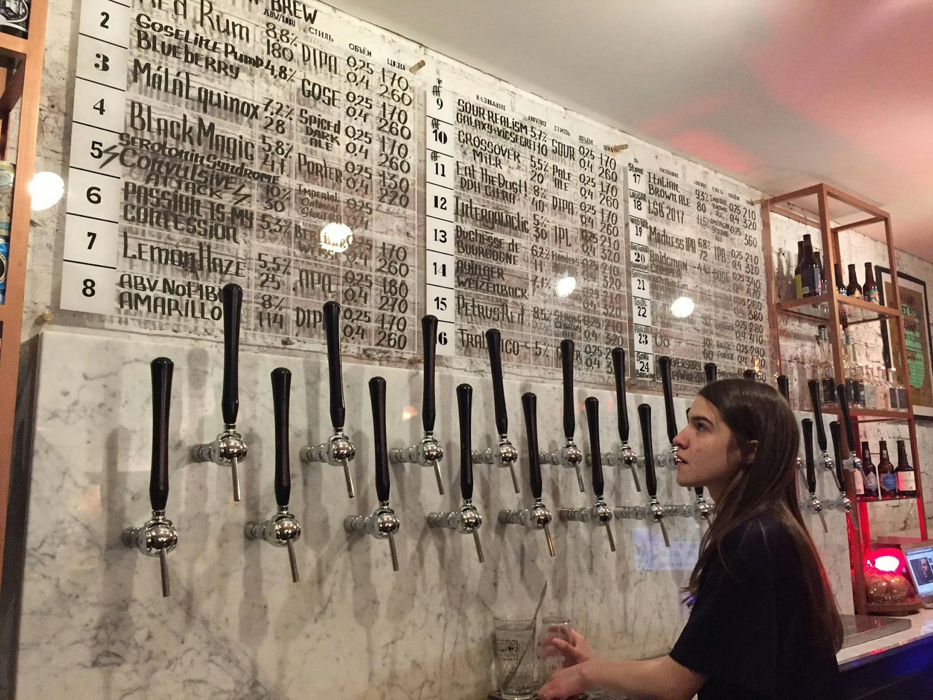 A bar lady pours a beer from a selection of taps at Redrum in St Petersburg © Megan Eaves / Lonely Planet