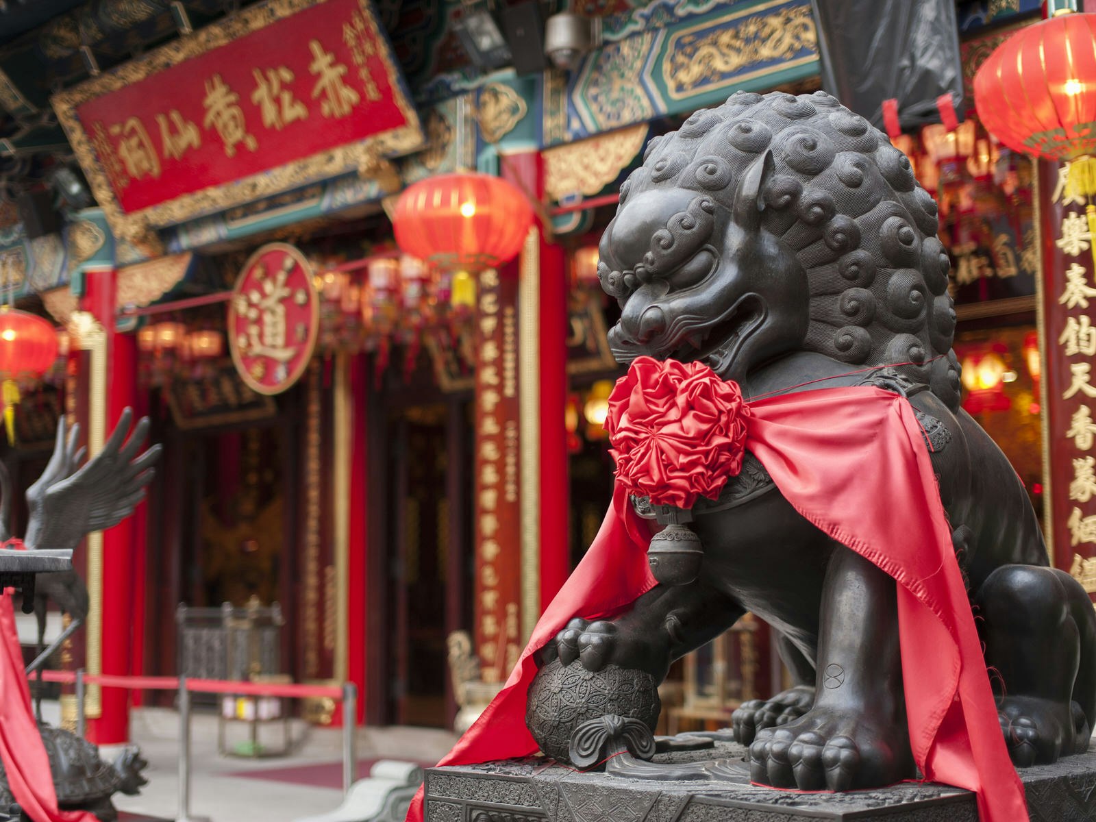 A Guardian lion – known as a fu dog – decorated in new year red ribbon at Wong Tai Sin Temple © Lee Yiu Tung / Shutterstock