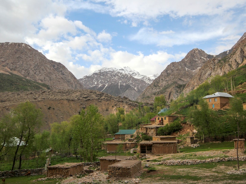 A hamlet along the popular 'Seven Lakes' trekking route, with mud buildings terraced up a small slope and backed by huge snowy mountain peaks © Stephen Lioy / Lonely Planet