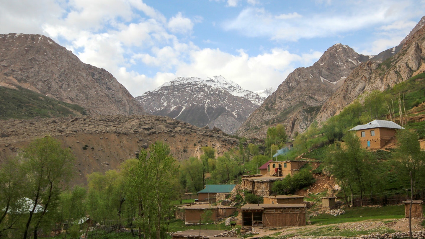 A hamlet along the popular 'Seven Lakes' trekking route, with mud buildings terraced up a small slope and backed by huge snowy mountain peaks © Stephen Lioy / Lonely Planet