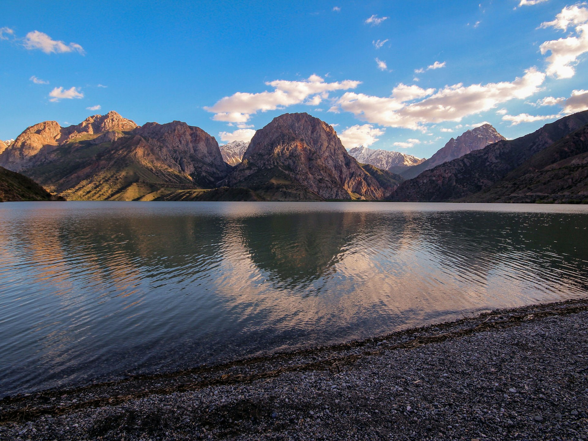 The shore of Iskander-Kul lake, with a pink sunset falling on the mountain peaks beyond © Stephen Lioy / Lonely Planet