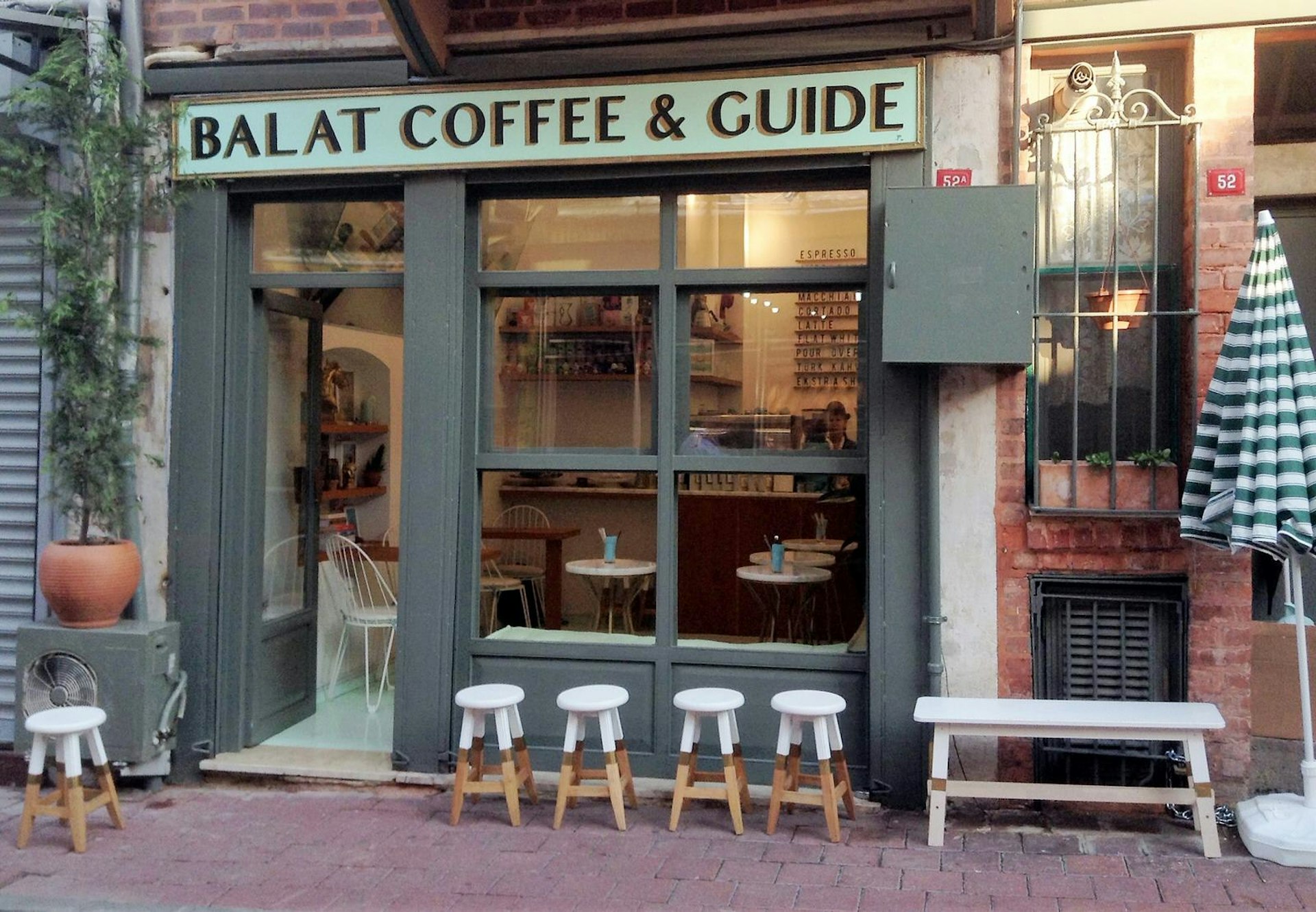 A row of wooden stools that have been dipped in white paint sit outside Balat Coffee & Guide which supports the neighbourhood communities © Jennifer Hattam / Lonely Planet 