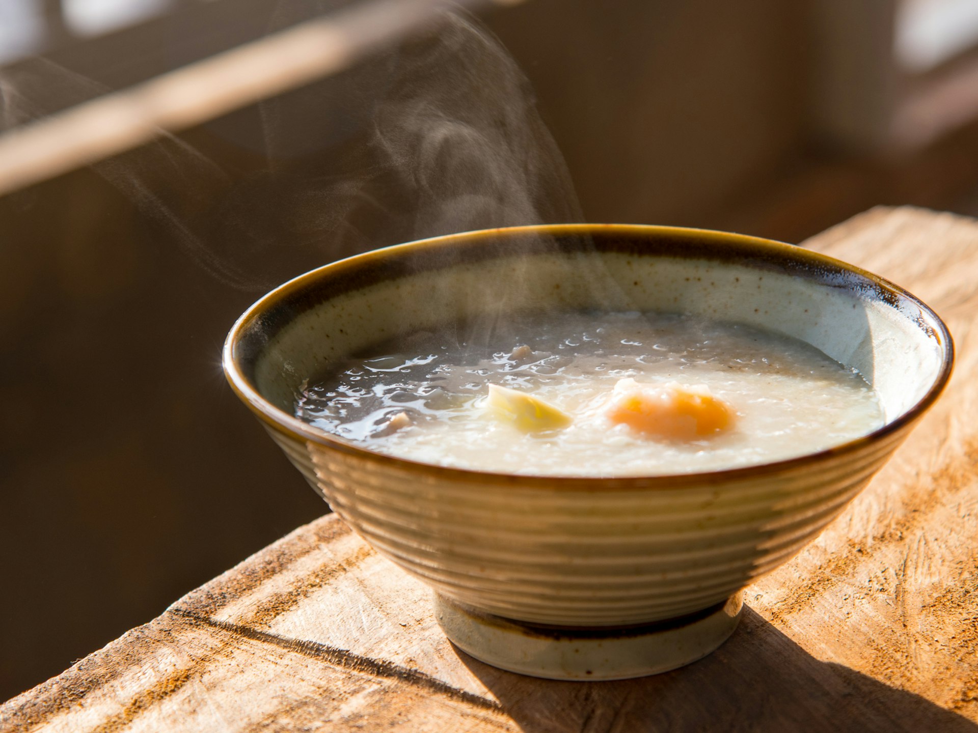 A steaming bowl of congee on a wooden table in China