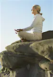 A woman mediates on a cliff over looking the pacific ocean near San Diego © Brad Wilson / Getty Images