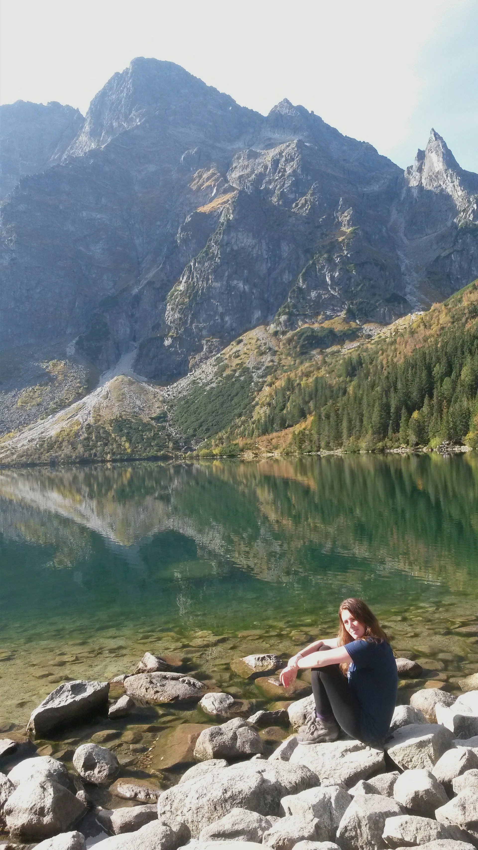 Image of Lonely Planet Local Amy sitting beside Morskie Oko Lake, with mountains in the background.