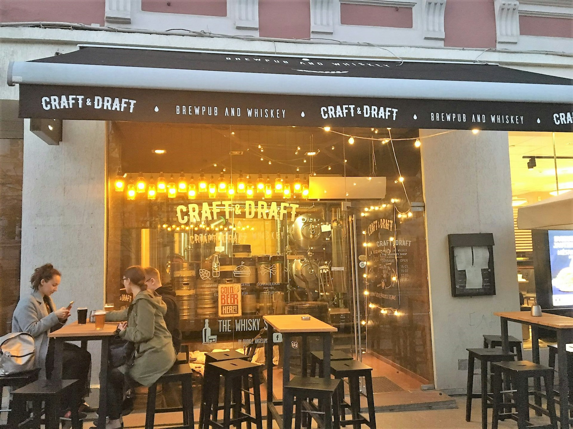 Three patrons sit at high tables drinking beer outside Craft & Draft © Gemma Graham / Lonely Planet