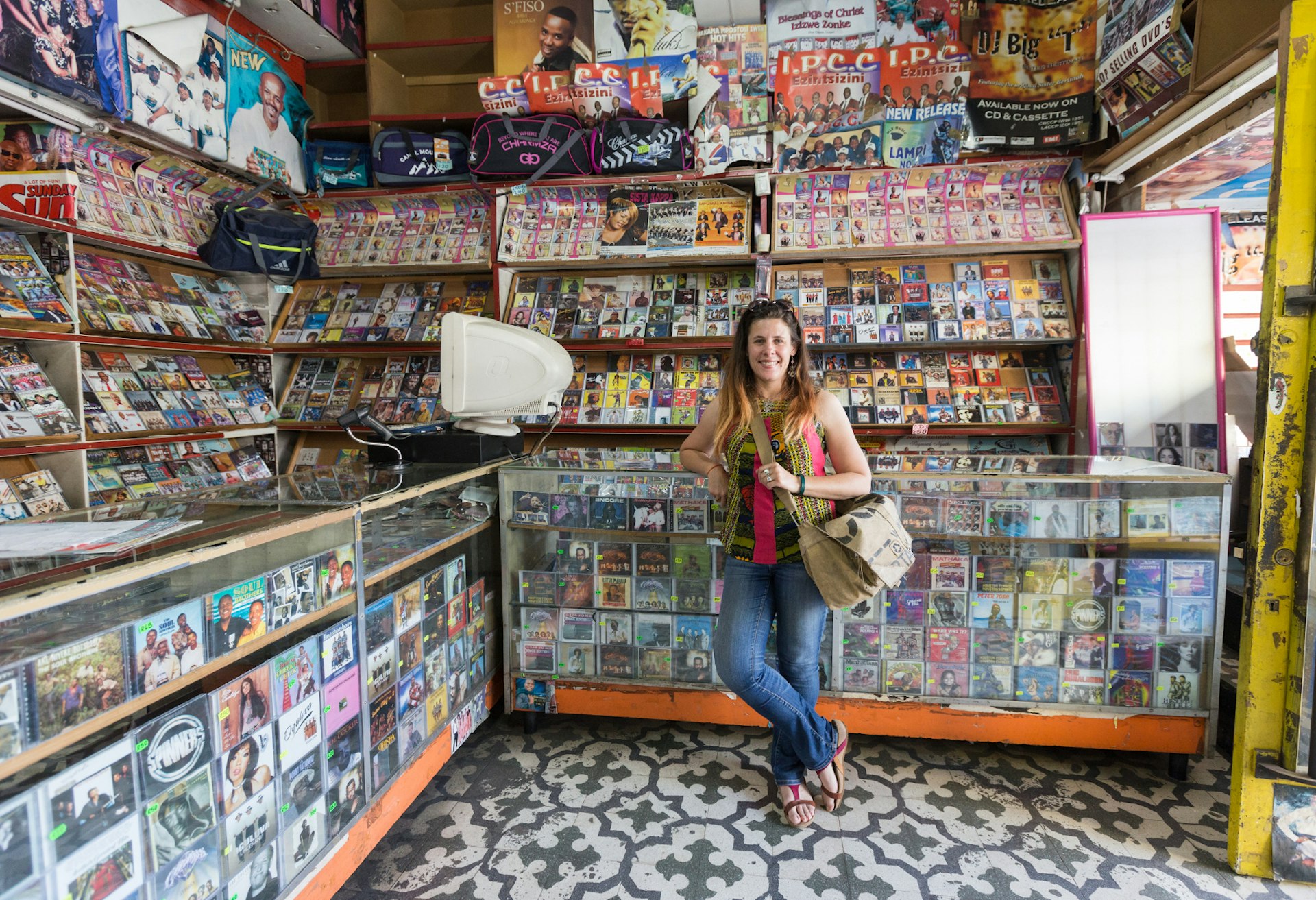 The writer Heather Mason stands smiling and surrounded by cds and cassettes in the Vinyl Joint on Eloff Street, downtown Johannesburg © Heather Mason / Lonely Planet