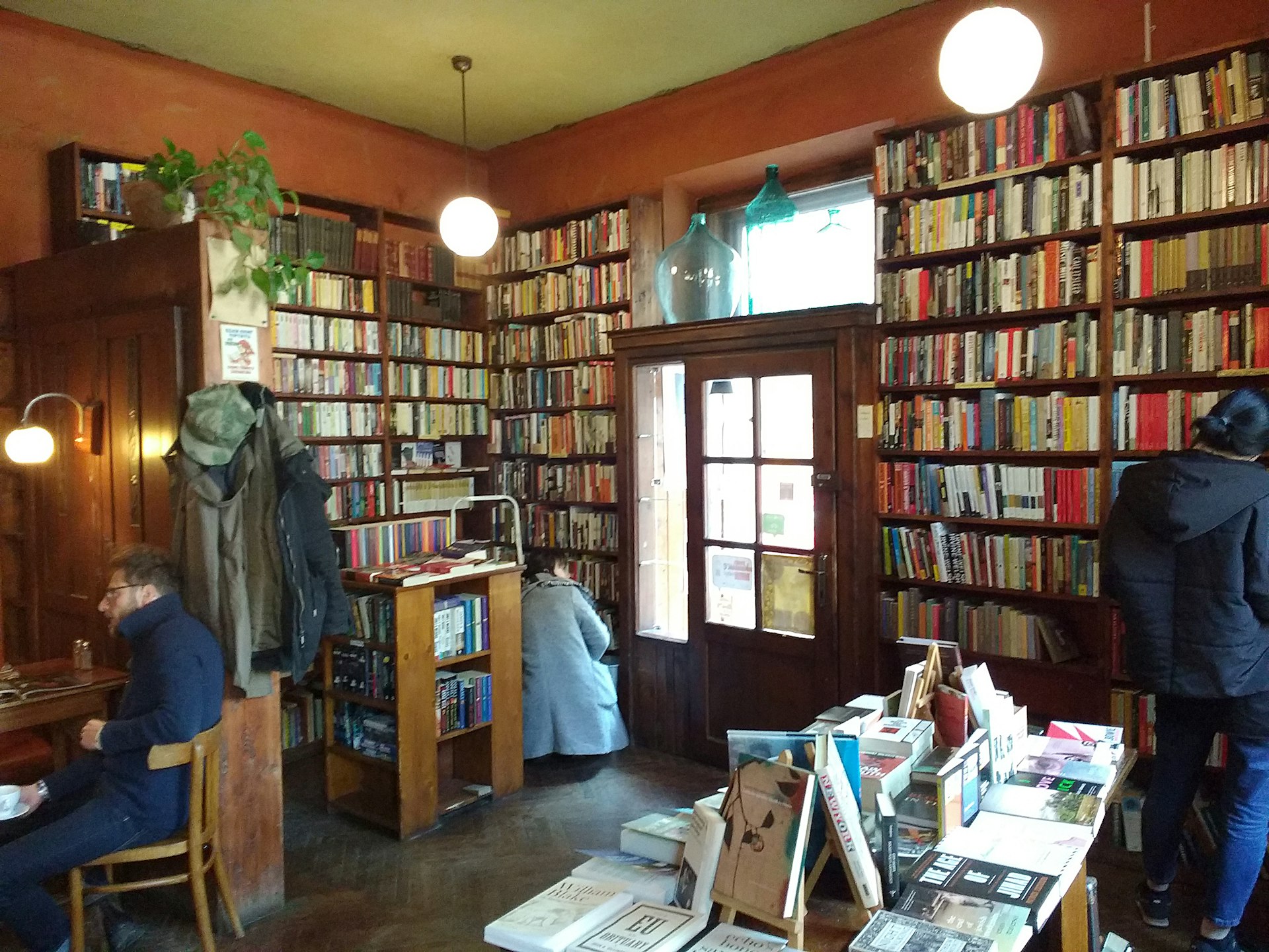 Interior shot of Massolit Books & Cafe, showing people browsing the books in the floor-to-ceiling bookcases.