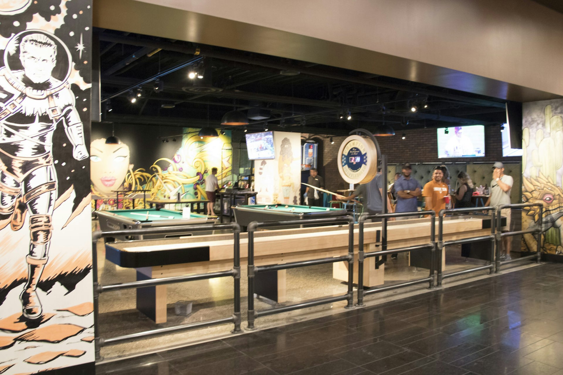 A row of shuffleboard tables enclose a gaming area, with pool tables in the background © Greg Thilmont / Lonely Planet