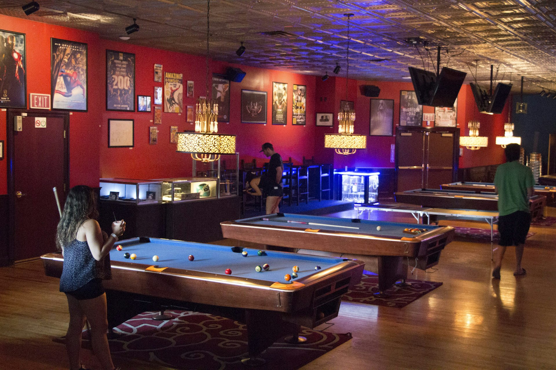 A row of pool tables is seen in a deep red room with movie posters all over the walls. © Greg Thilmont / Lonely Planet